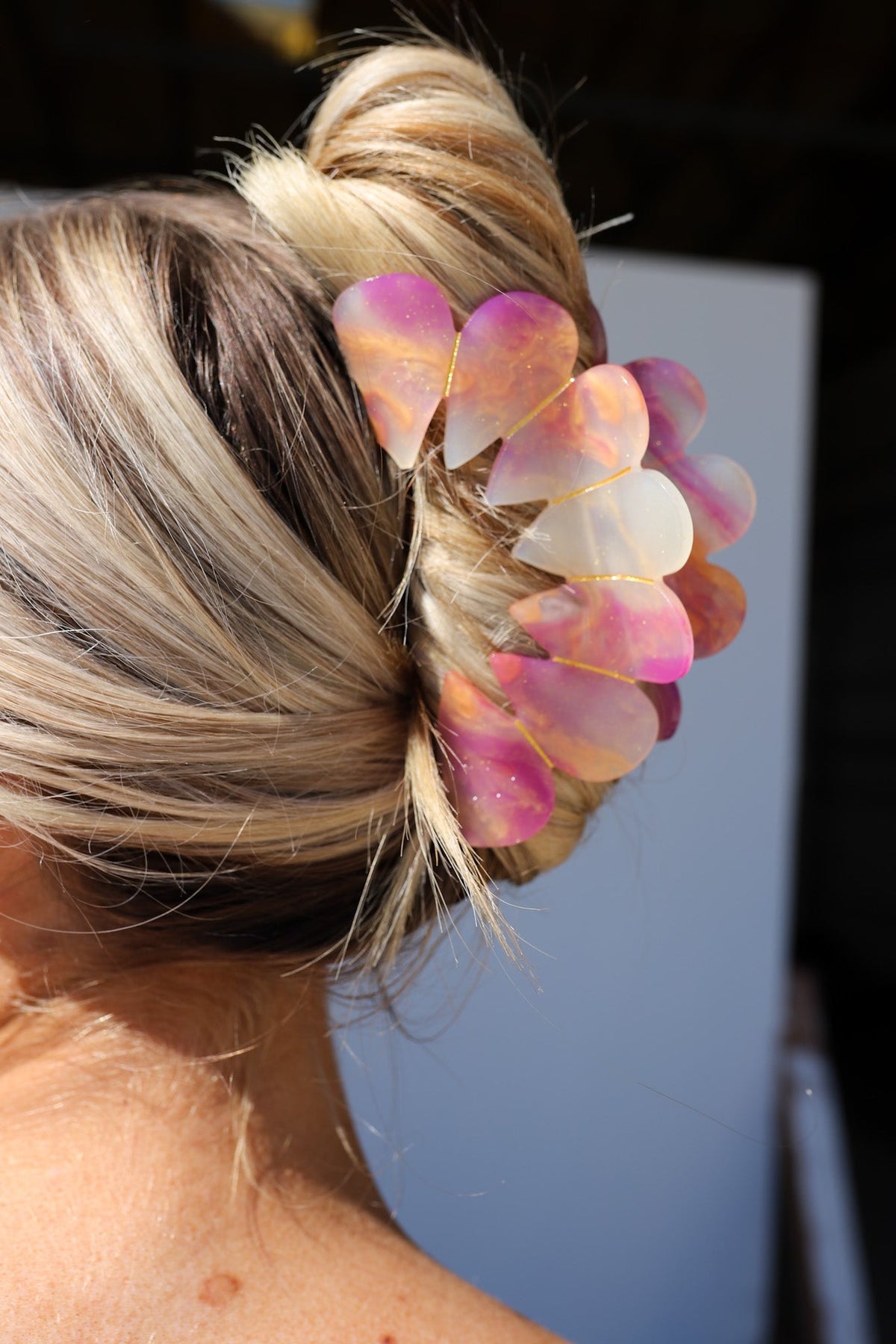 Close-up of pink and peach heart hair claw clip attached to blonde hair