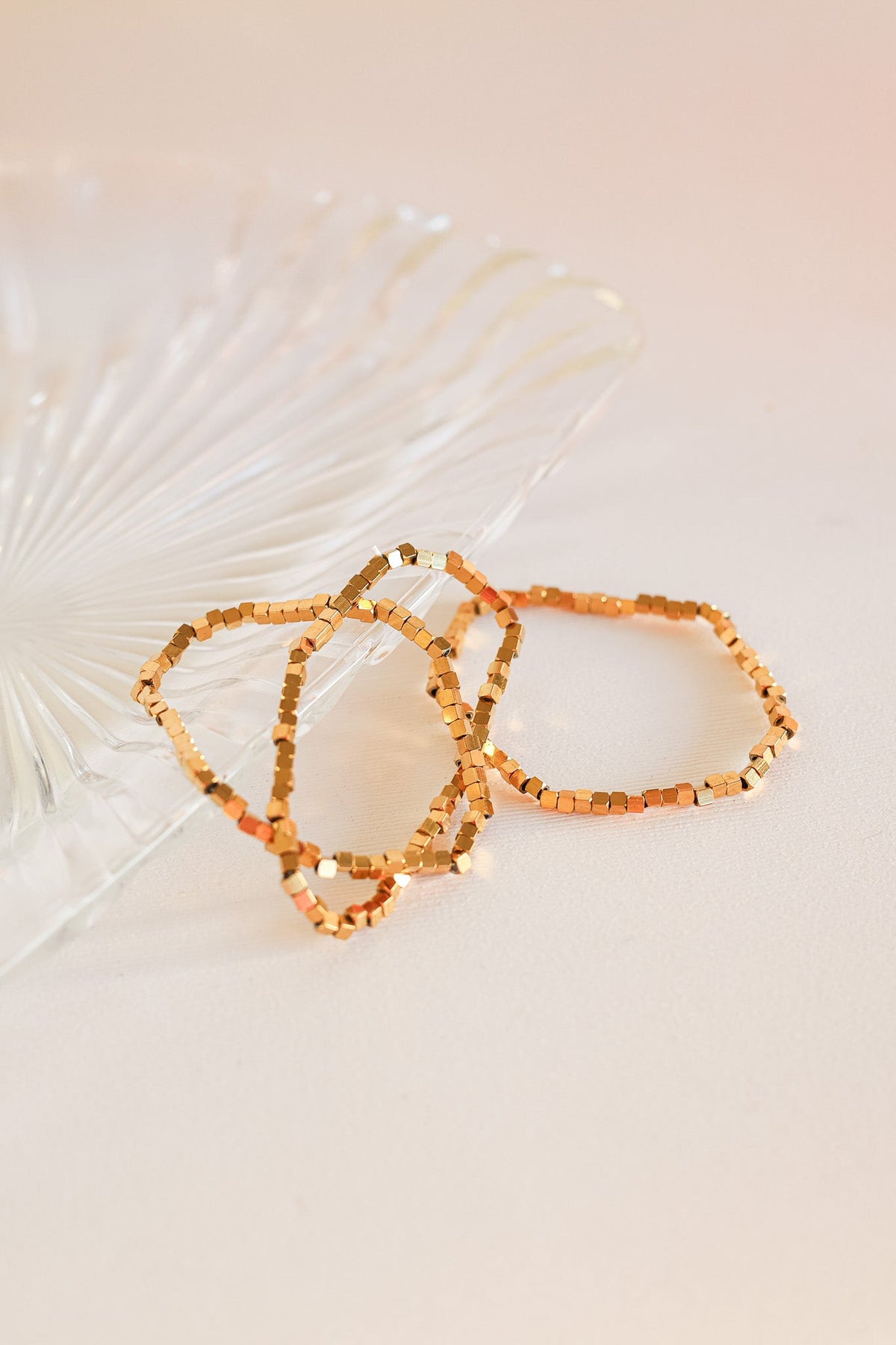 Gold Ember bracelets with small square beads arranged in a layered set