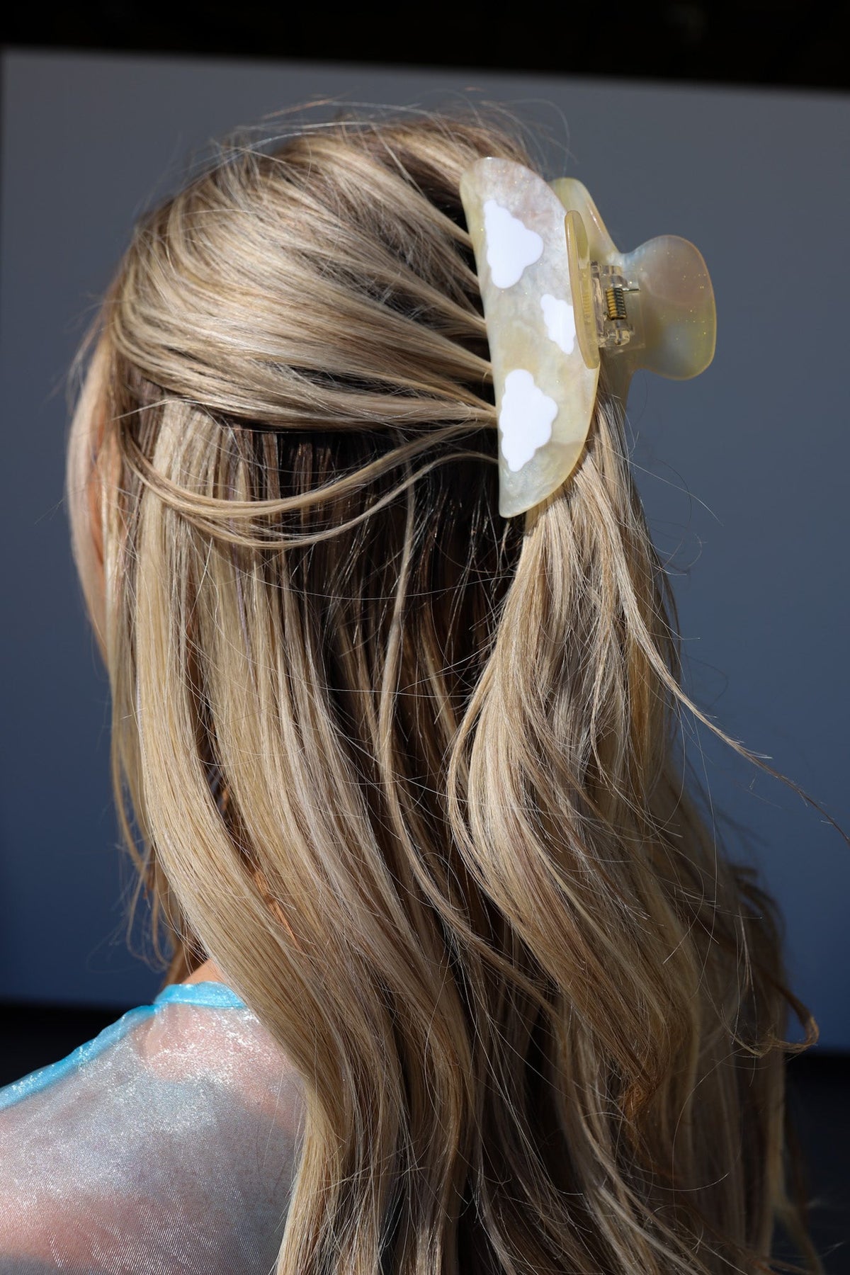 Close-up of white heart hair claw clip on blonde hair, angled view