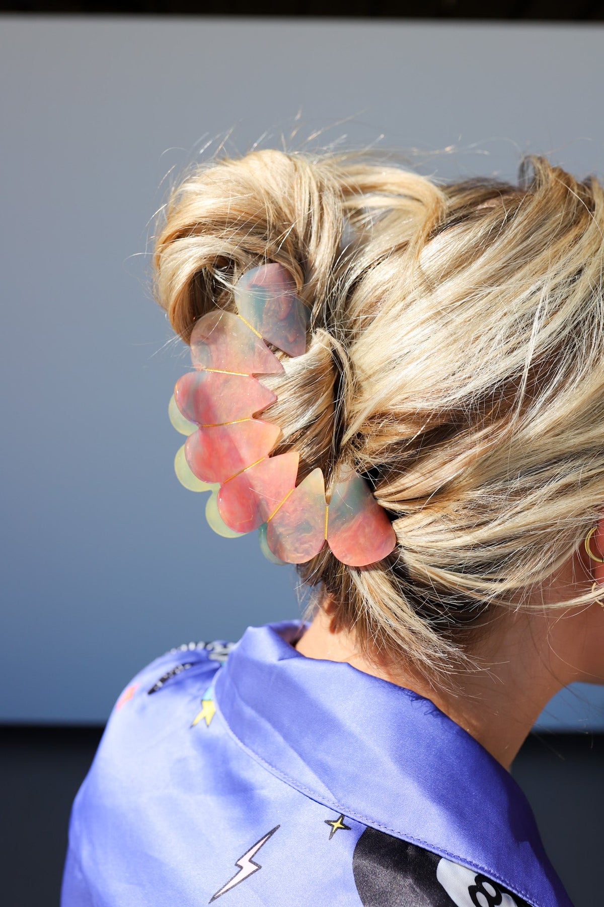 Pastel translucent hair claw clip holding blonde ponytail, close side view