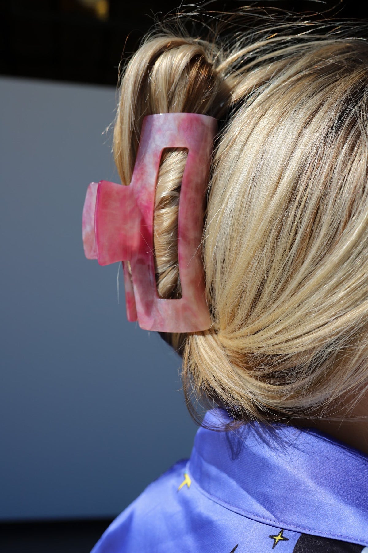 Pink translucent hair claw clip on blonde hair, profile close-up