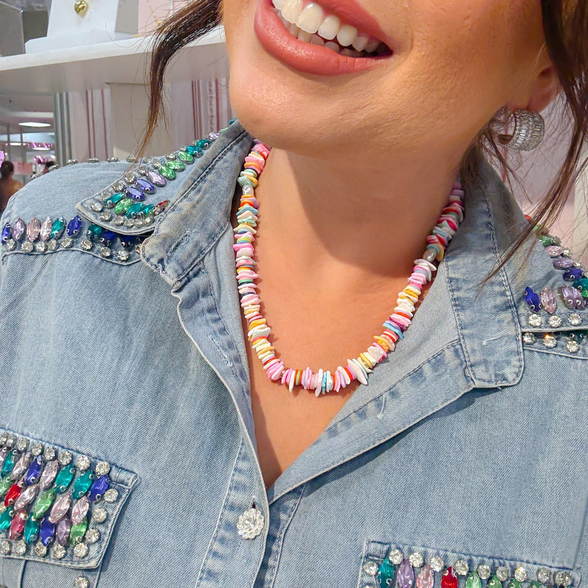 Pastel gemstone beaded necklace with rainbow disc beads along the neckline, close-up