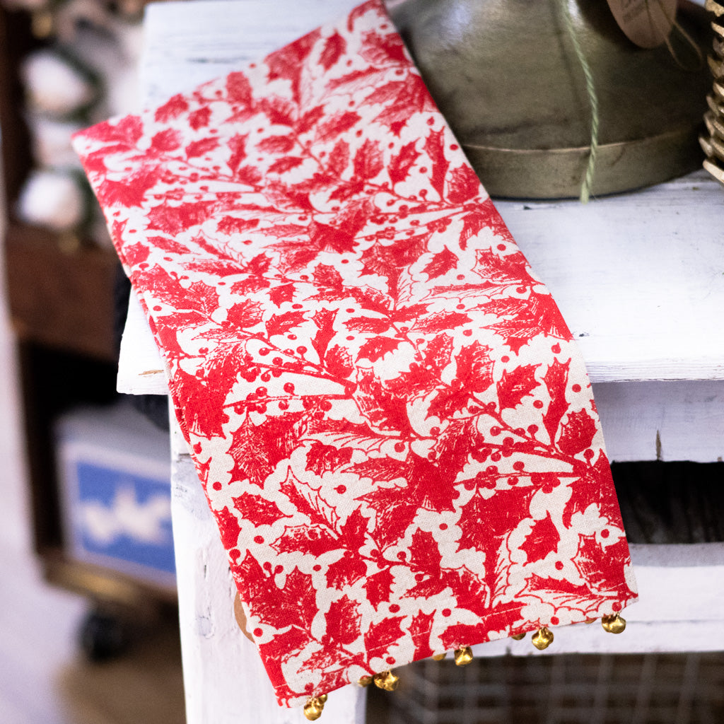 Red and white botanical print holiday towel with gold bell trim along the hem