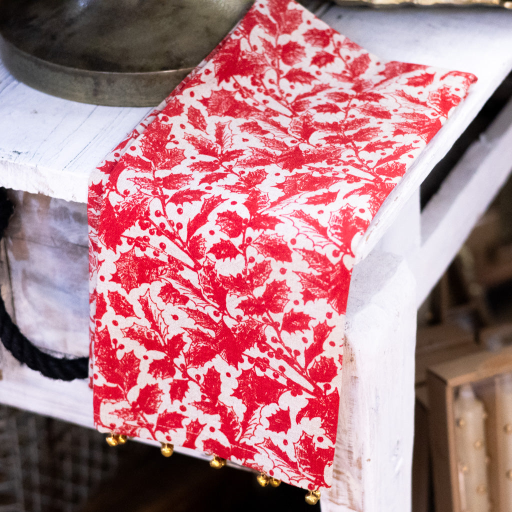 Red botanical print holiday towel with decorative hem and gold bell trim