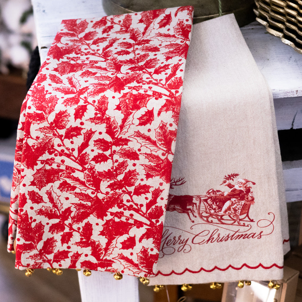 Holiday towel with red botanical print, gold bell trim, and “Merry Christmas” text