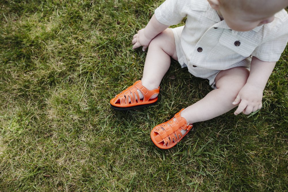 Kids orange barefoot sport sandals on grass, open-toe straps and cushioned sole