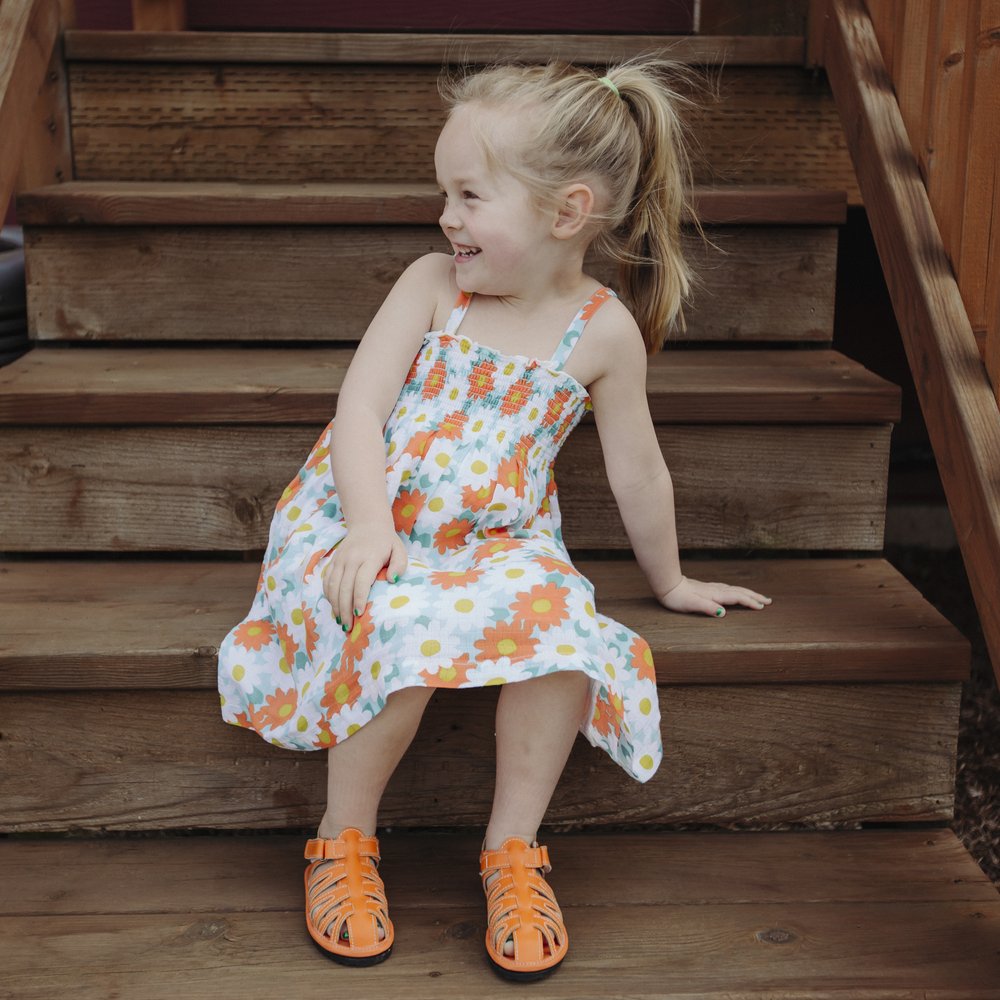 Child wearing orange barefoot sport sandals with hook-and-loop ankle straps