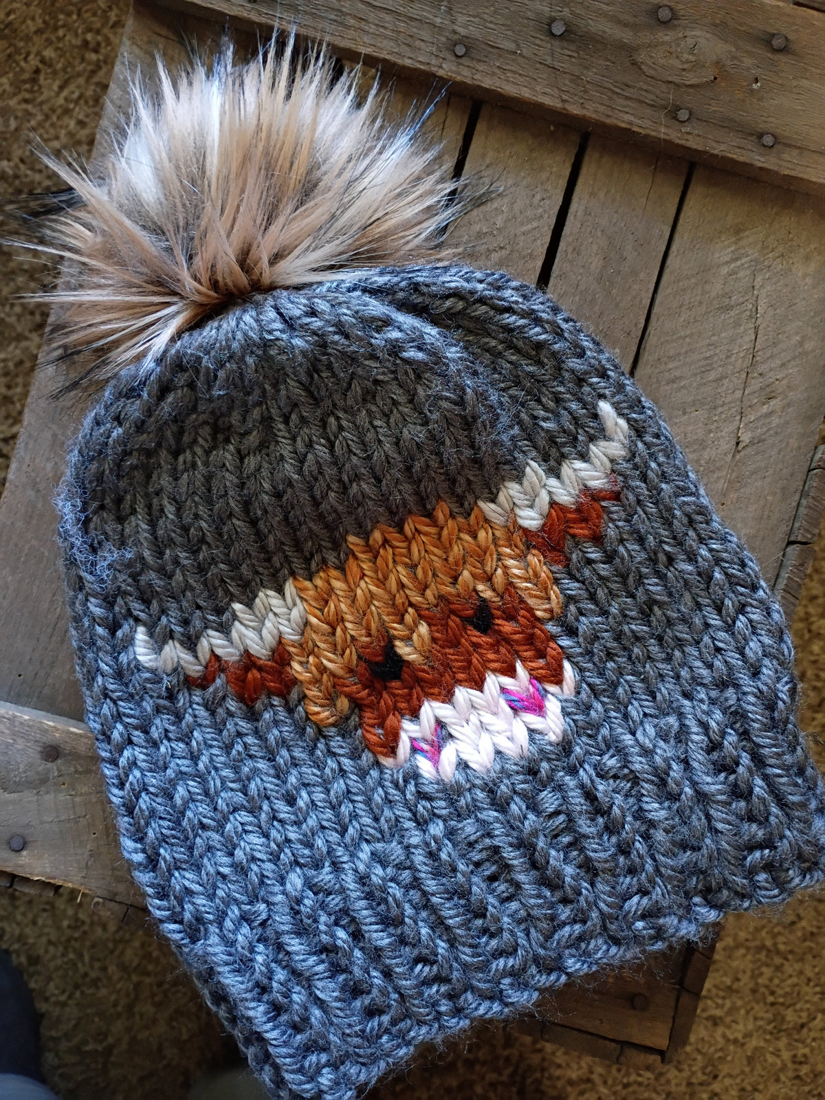 Charcoal knit beanie with tall faux-fur pom-pom and blue cow intarsia