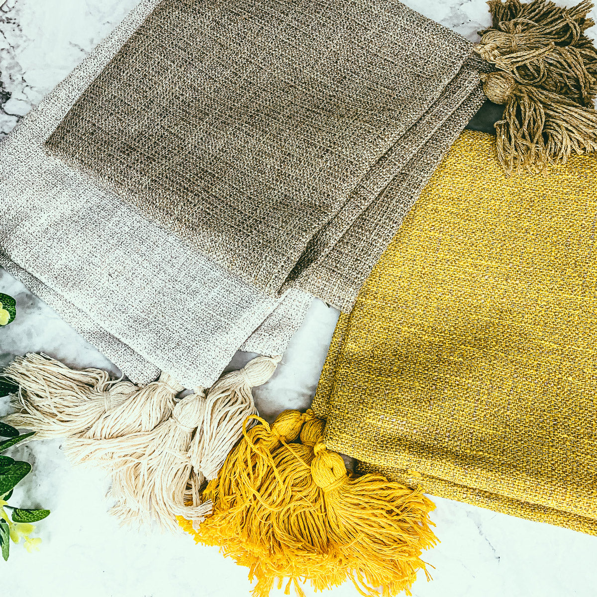 Linen-look pillow cases in light gray and mustard yellow, with tasseled fringe