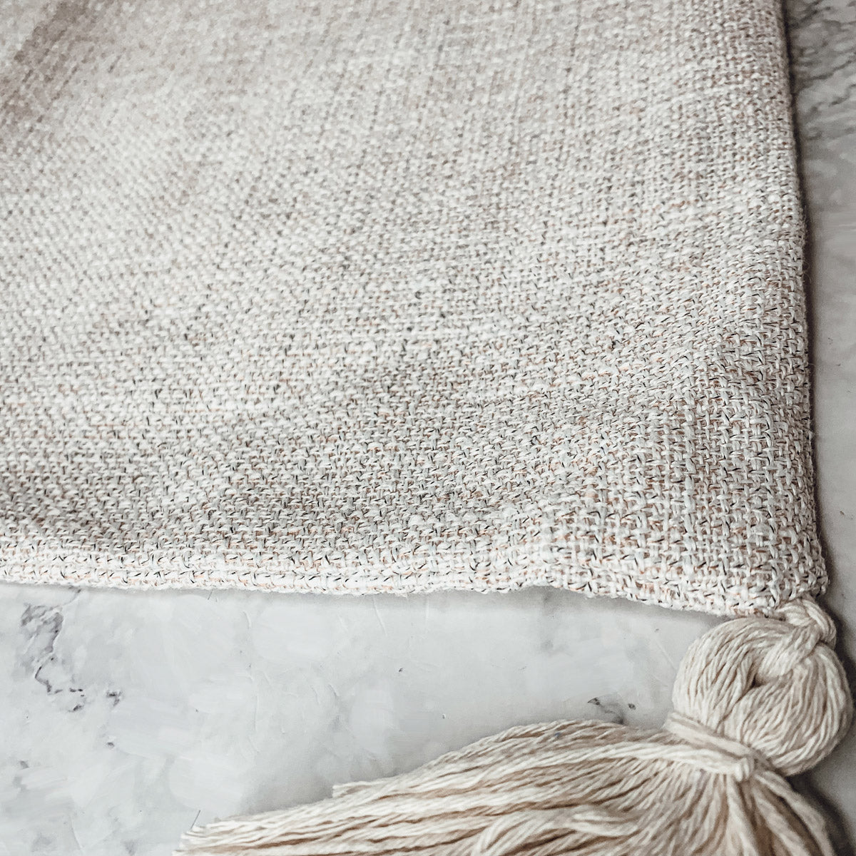 Boho cottage pillow case in light gray with braided tassel knot on corner.