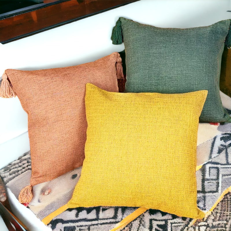 Boho cottage pillow cases in peach, yellow, and green with tassels on corners.