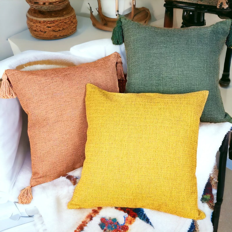 Set of linen-look square pillow cases in green, yellow, and terracotta with tassels