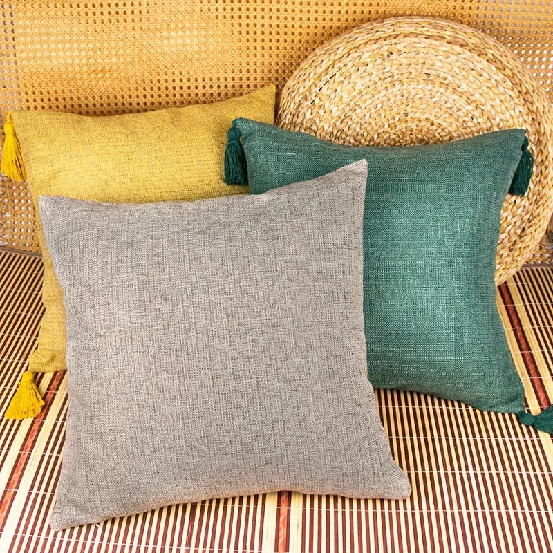 Boho cottage pillow cases in light gray and teal green with tassel accents.