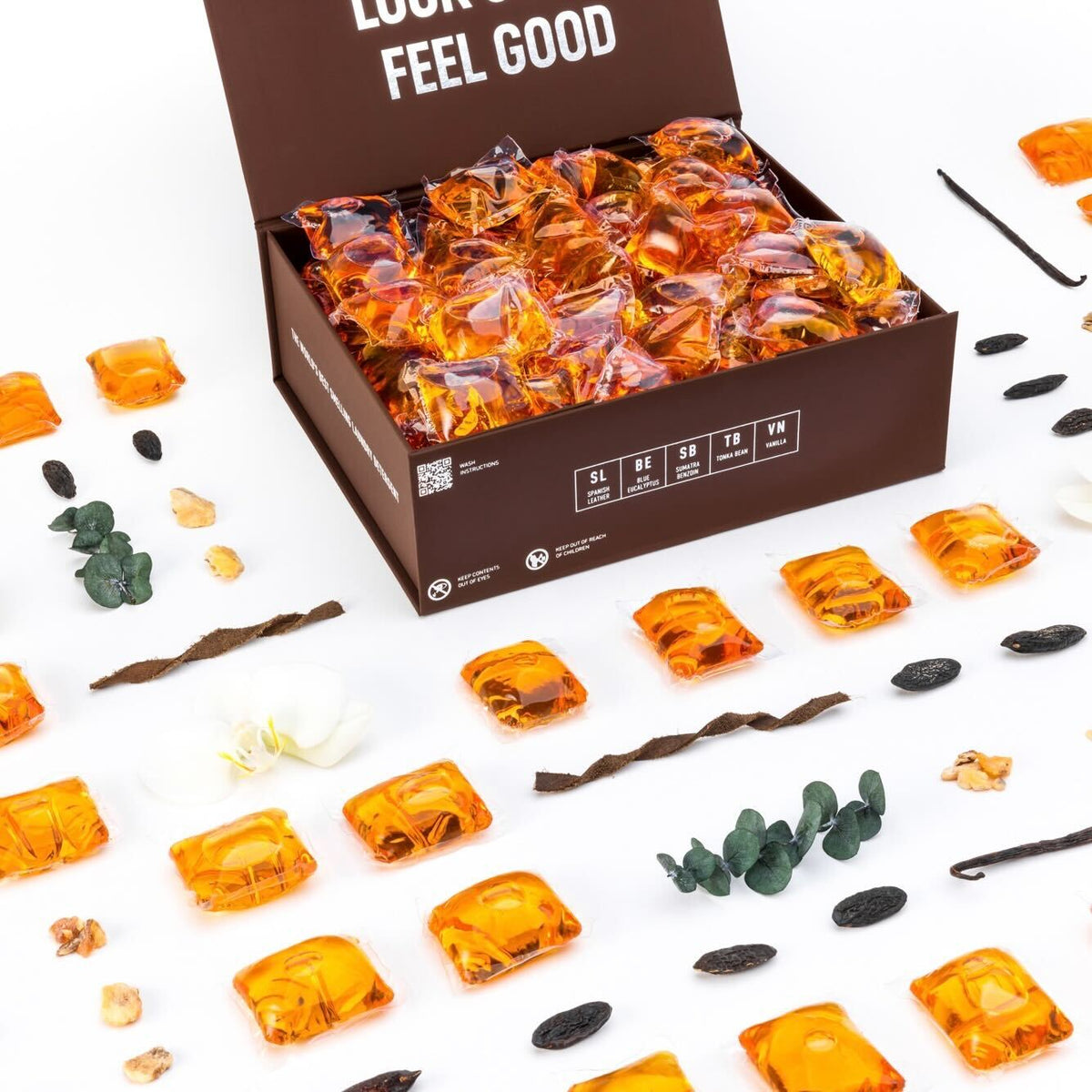 Open box of orange laundry detergent pods with sealed packets scattered around
