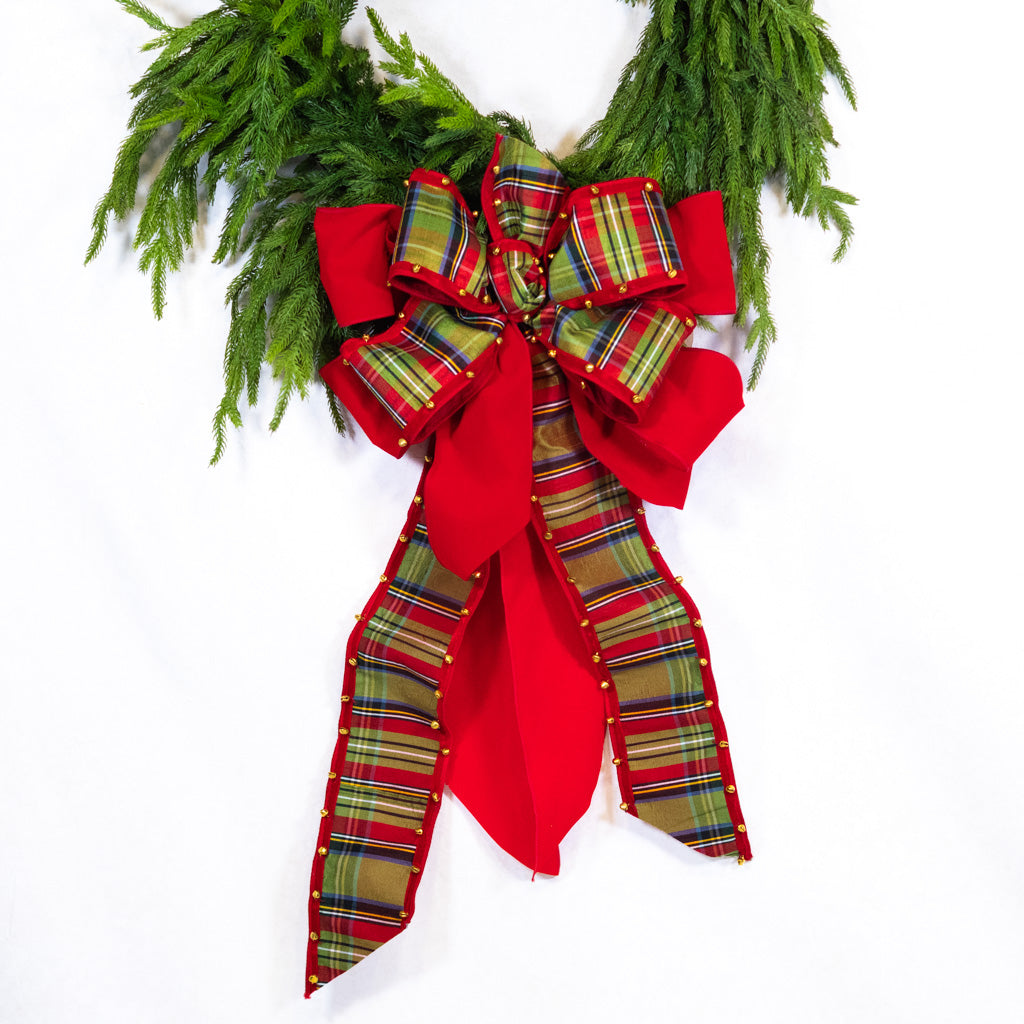 Red plaid bow with bell-edged loops, gold studs, and hanging ribbon tails