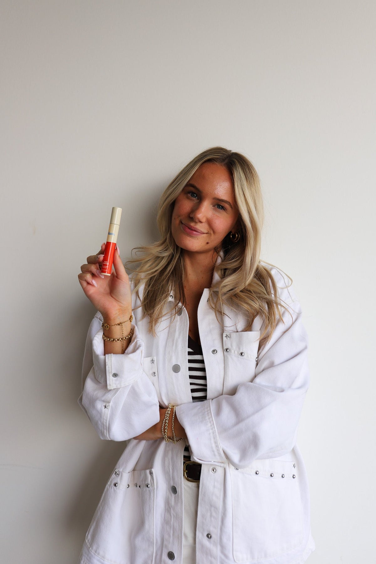 Hair perfume spray bottle held by woman in white jacket
