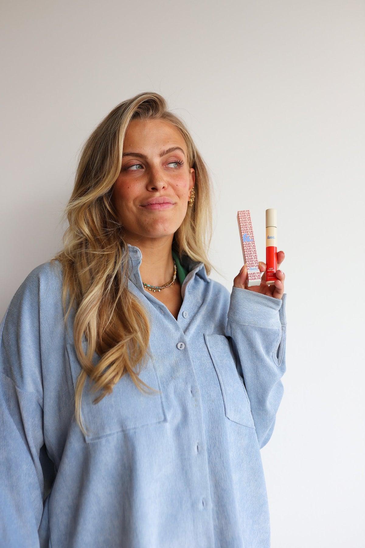 Hair perfume spray bottle held by woman in light blue top