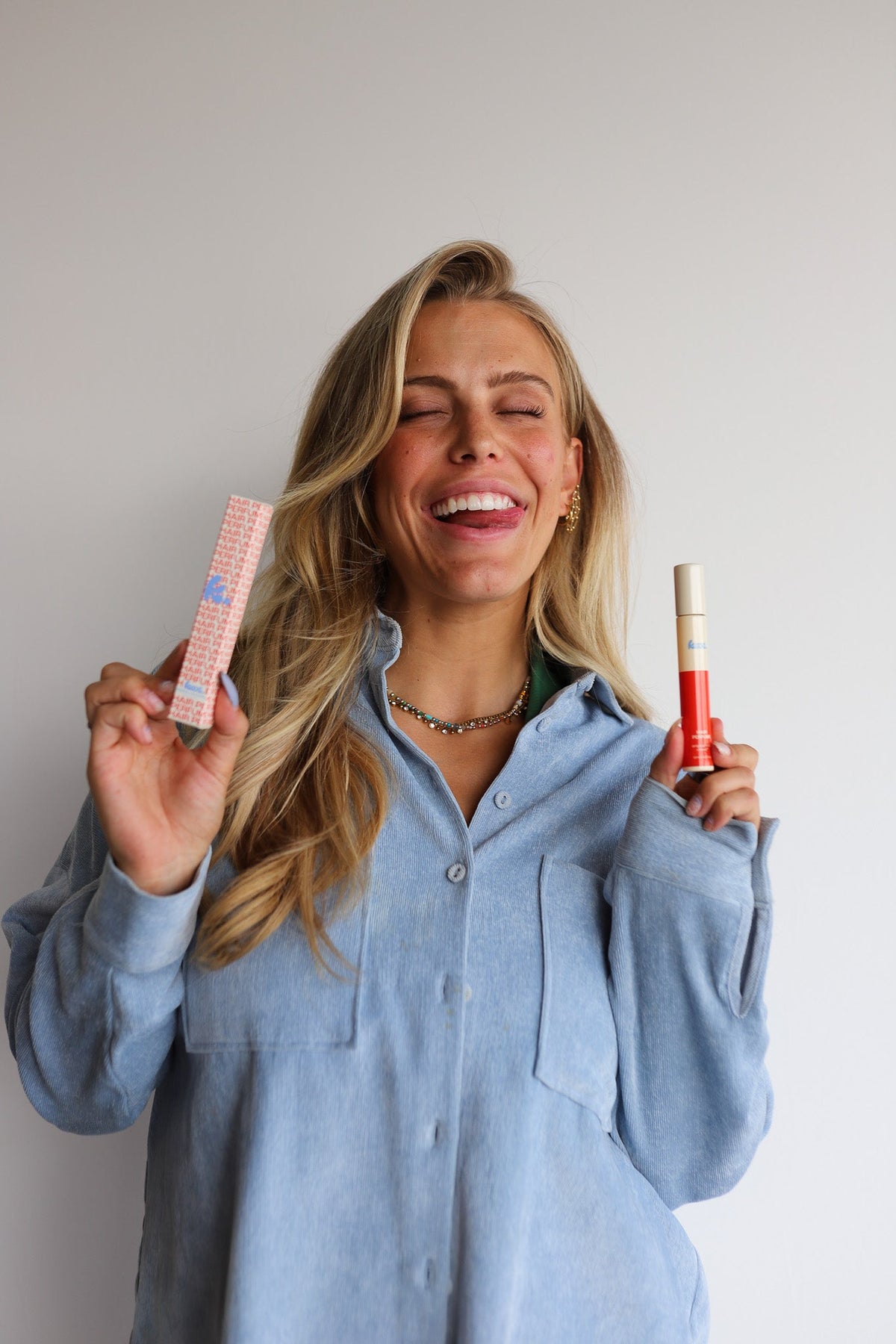 Woman holding hair perfume spray bottle and a matching box while smiling