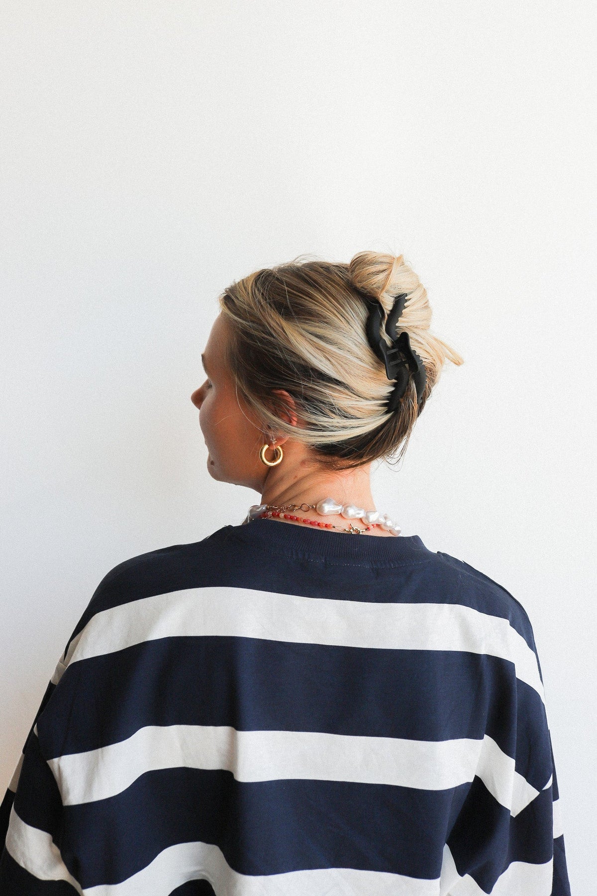 Wavy hair claw clipped in blonde hair bun, black accessory visible
