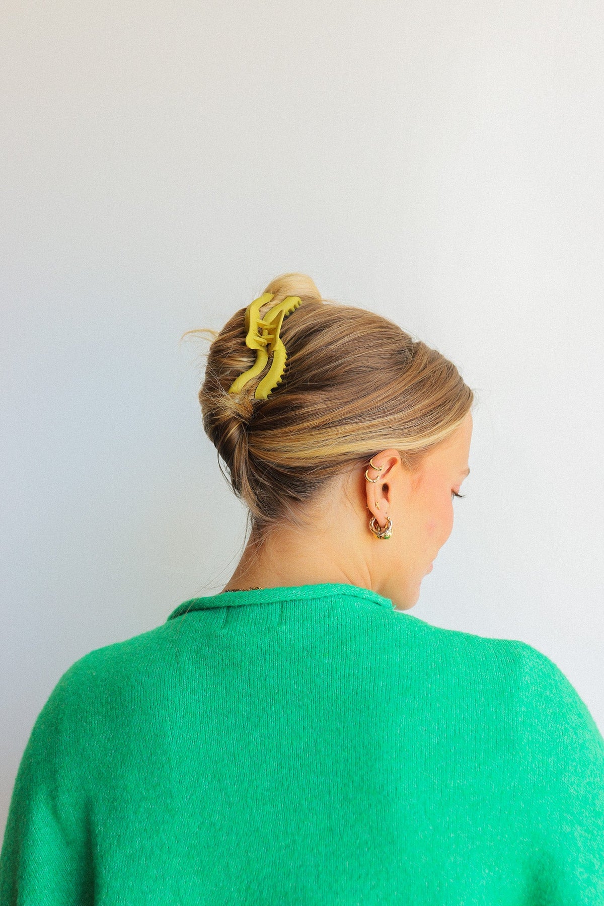 Yellow wavy hair claw clip holding a low bun from the side