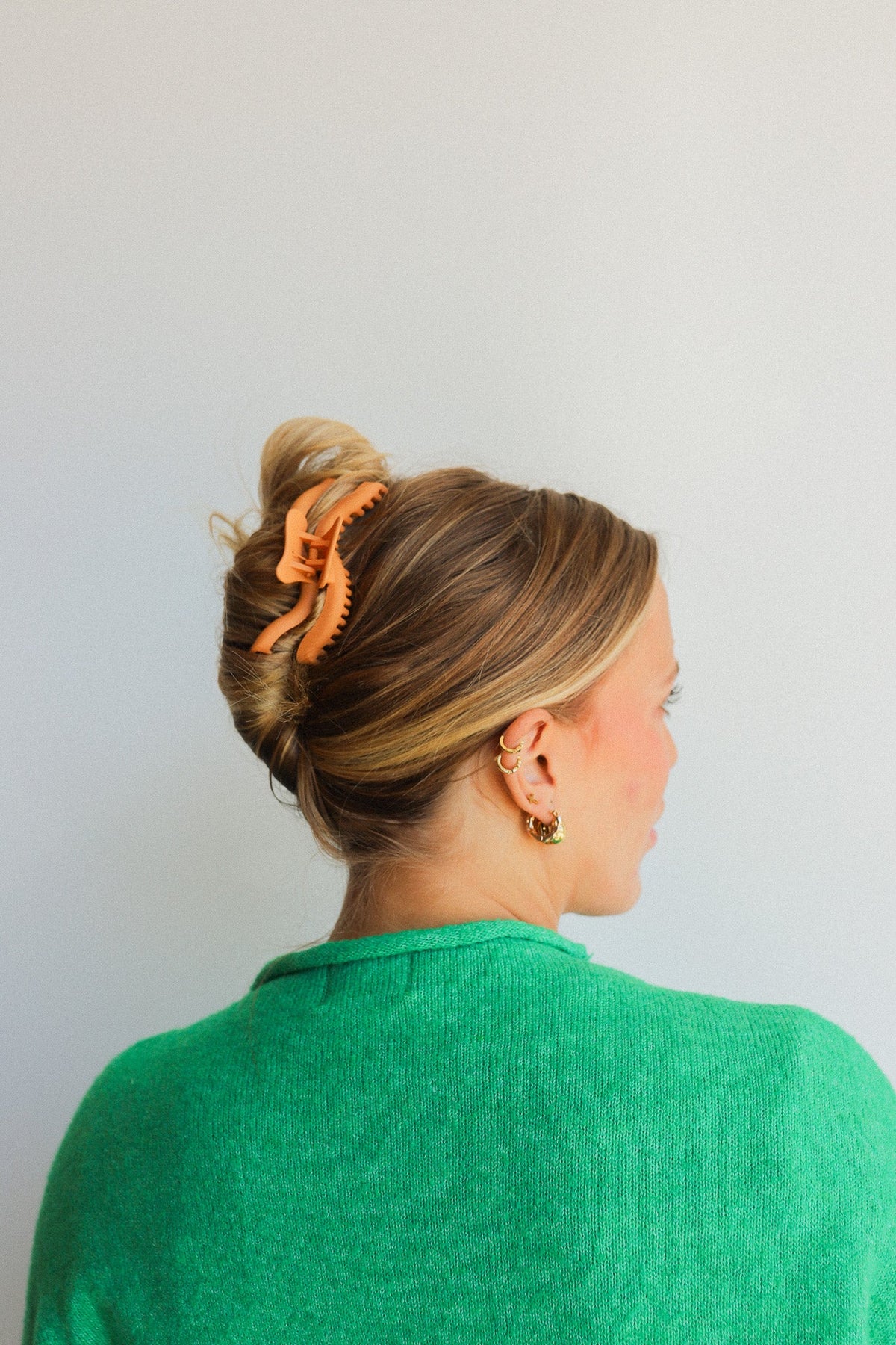 Wavy hair claw clip in warm orange, holding blonde hair in a bun