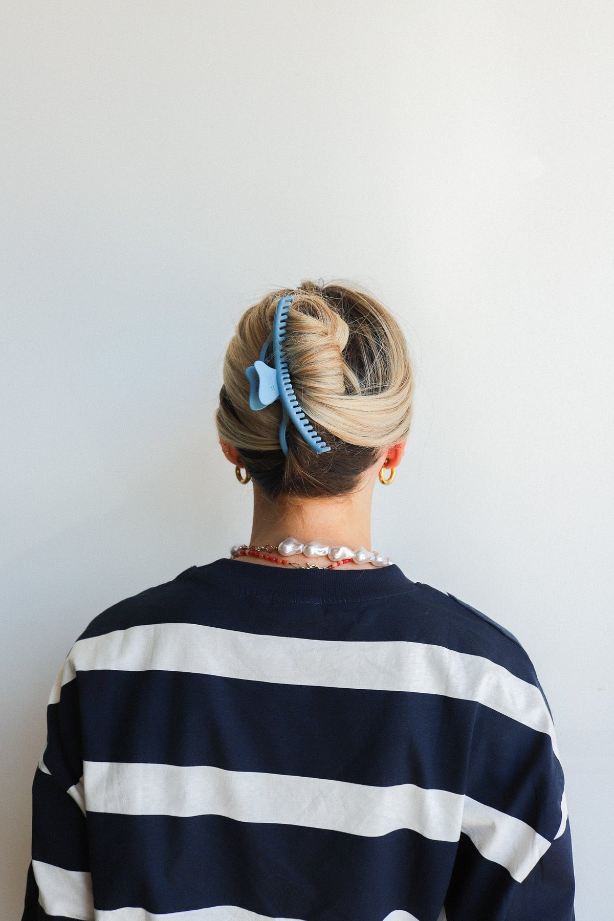 Wavy hair claw in light blue holding blonde hair in a bun