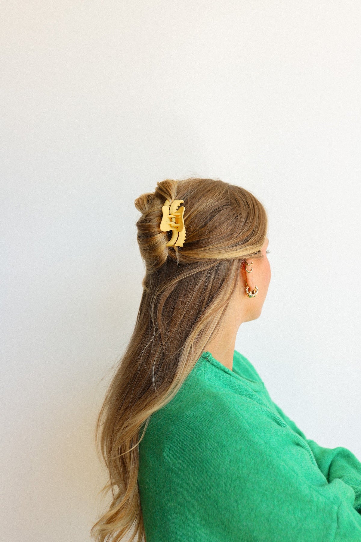 Wavy mini claw hair clip in gold tone on blonde hair, side view.