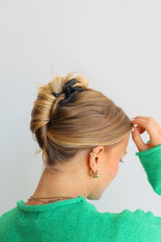 Black wavy mini hair claw on a blonde bun, worn on the side of the head