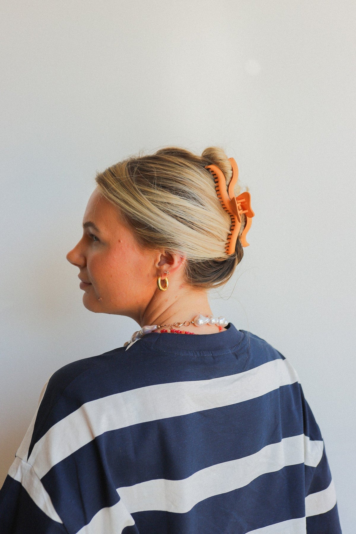 Orange-brown hair claw clip with curved comb teeth holding a side bun.