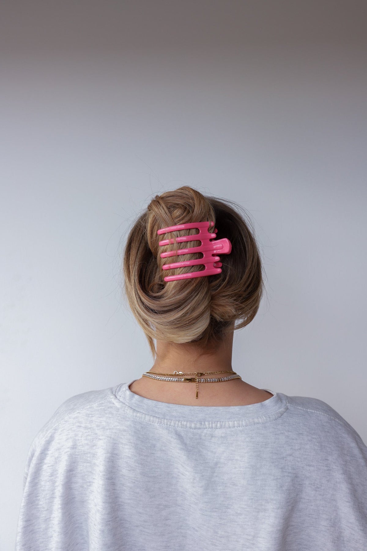 Wide pink hair claw with five teeth clipped in updo, back view