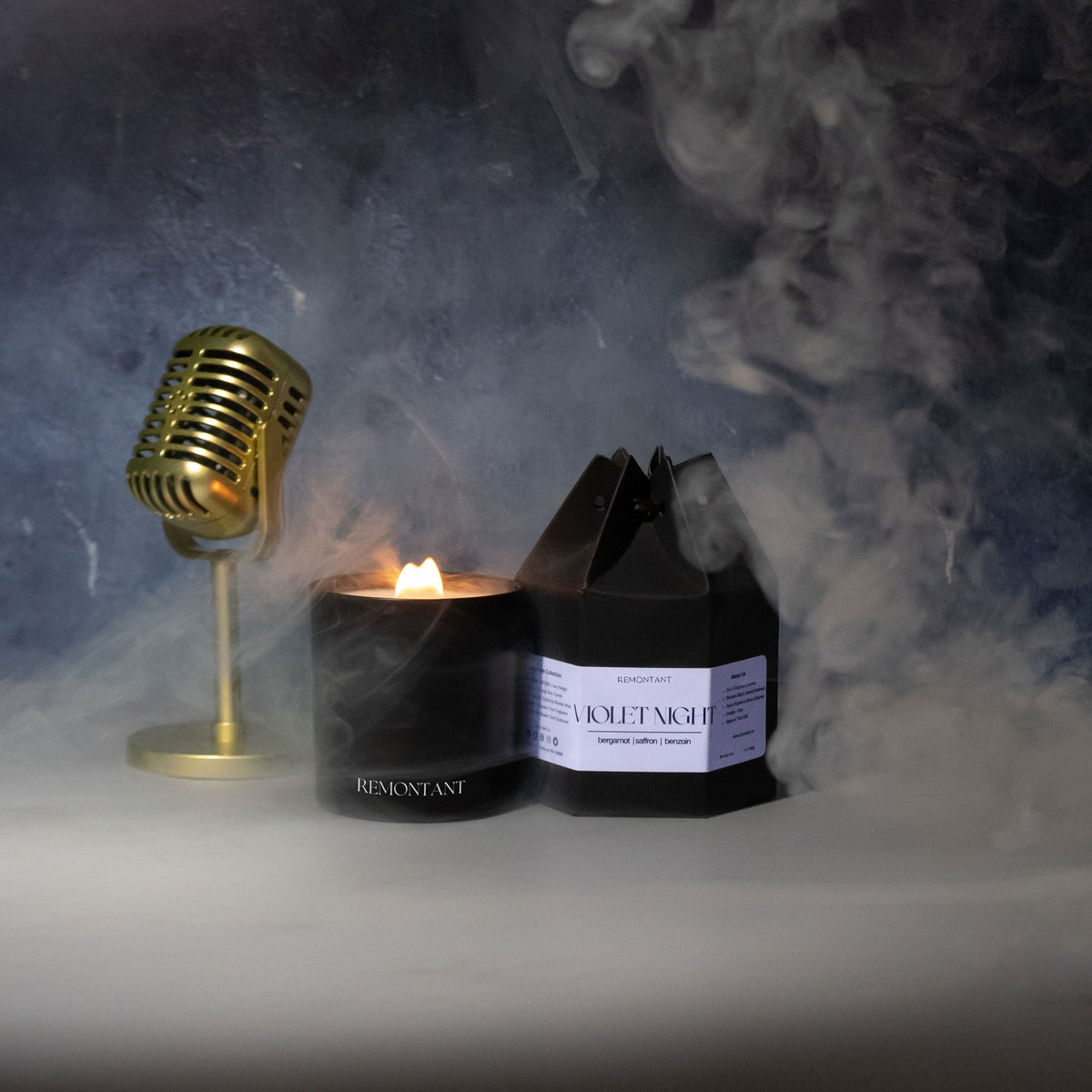 Violet Night candle beside its black package, with a lit wick
