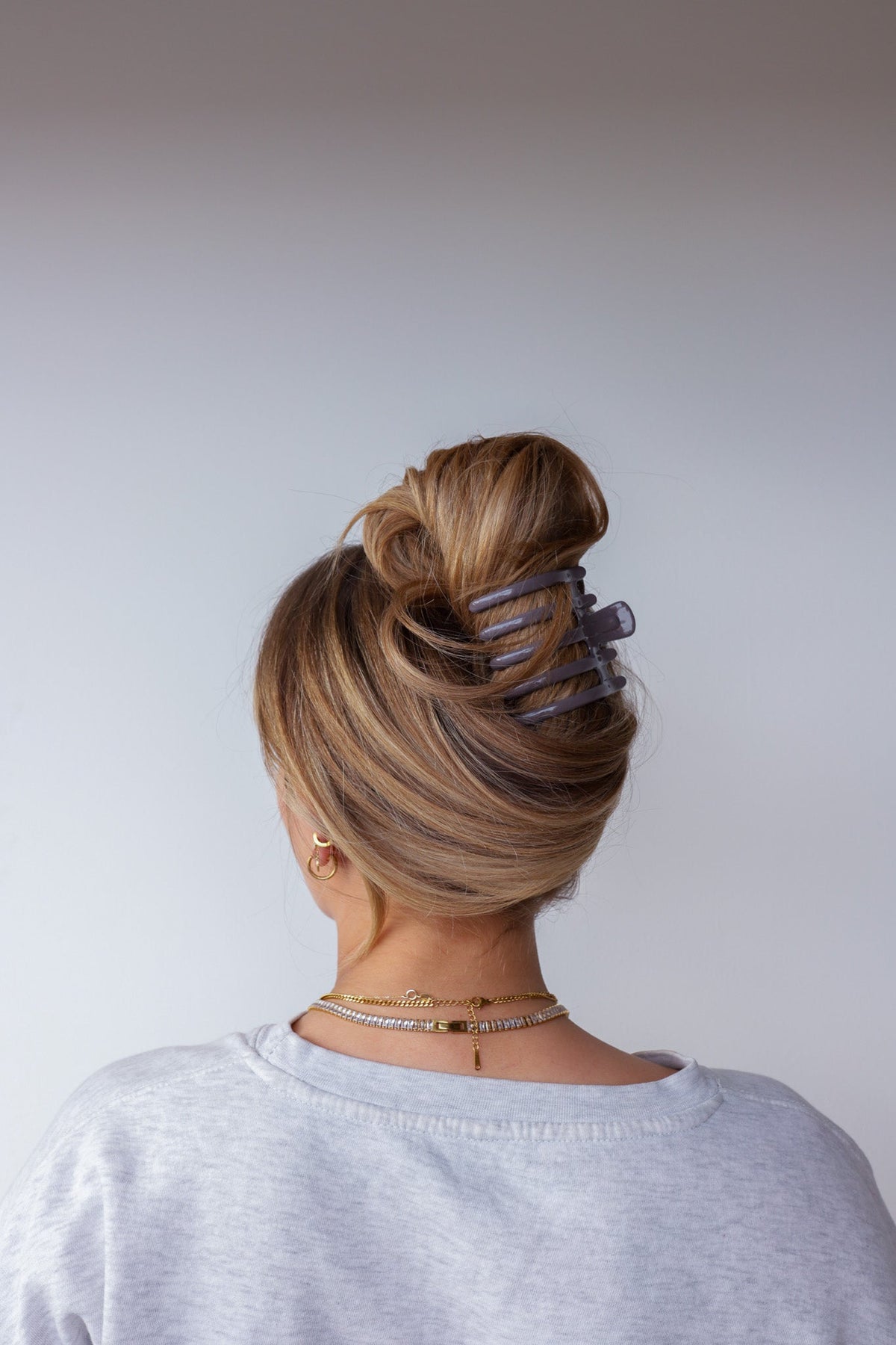 Wide lay down hair claw in shiny dark brown, clipped on blonde bun.