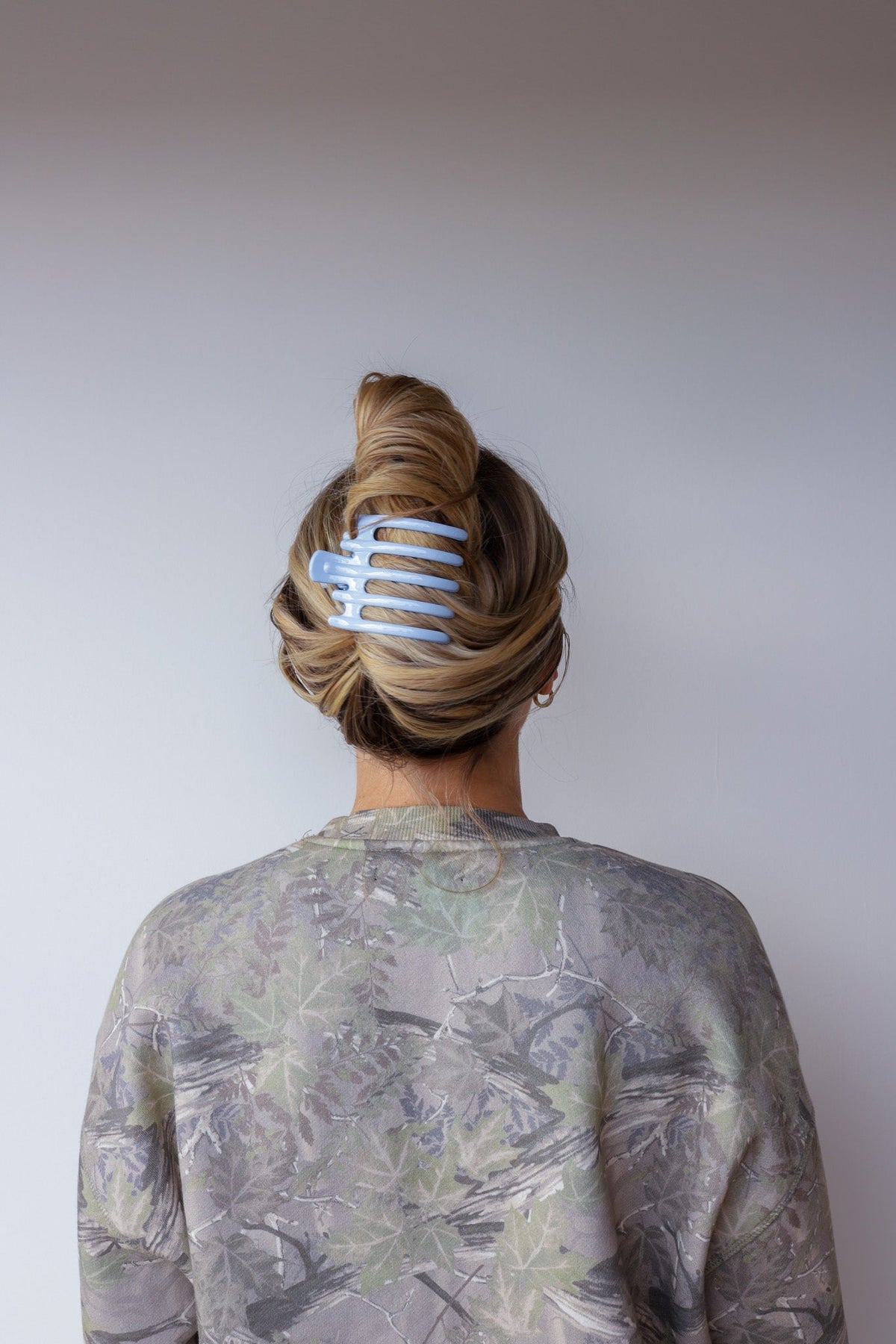 Wide lay-down claw hair clip in hair, glossy light blue with wide teeth.