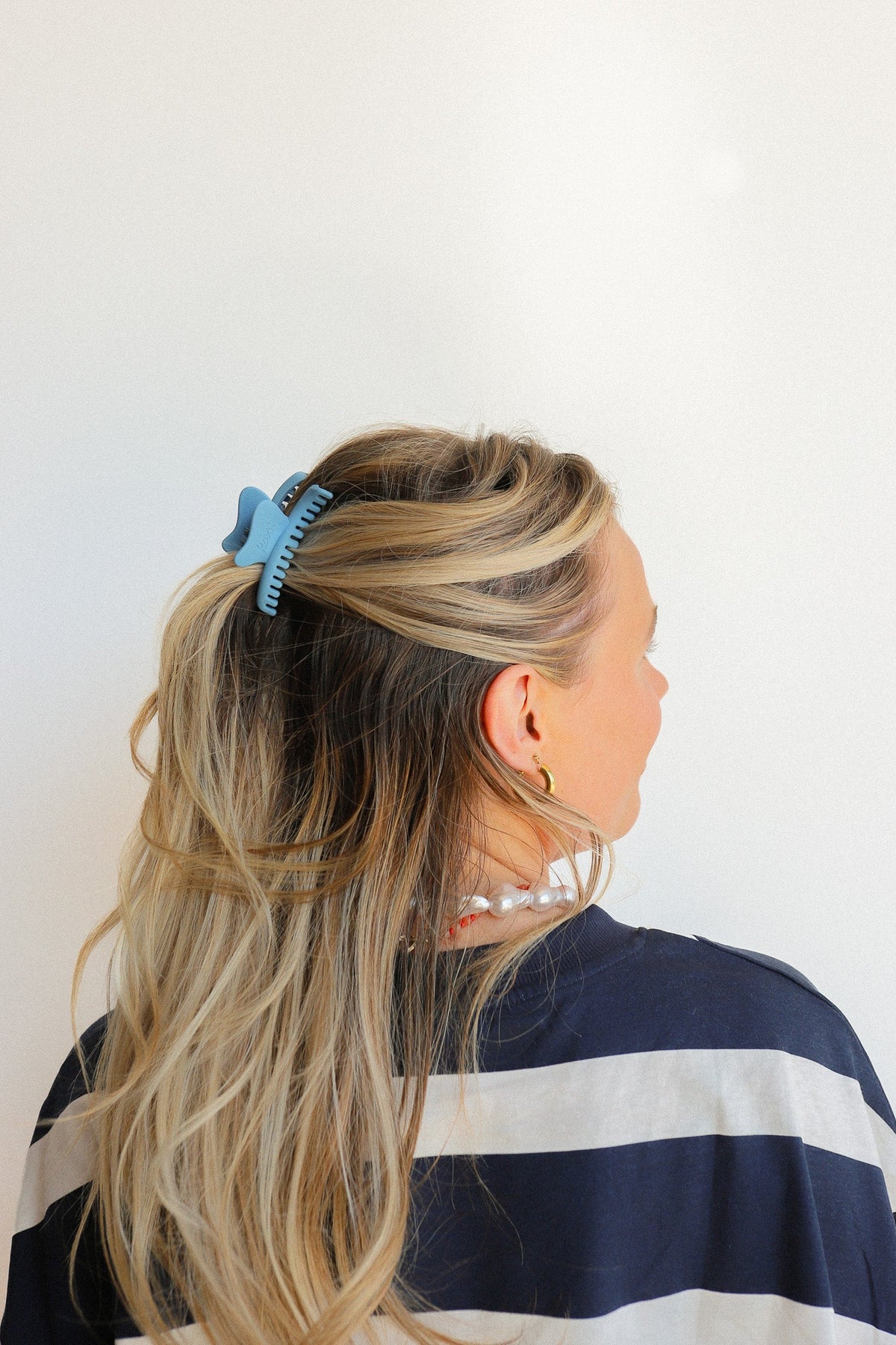 Wavy mini claw hair clip in teal-blue on long blonde hair, side view.