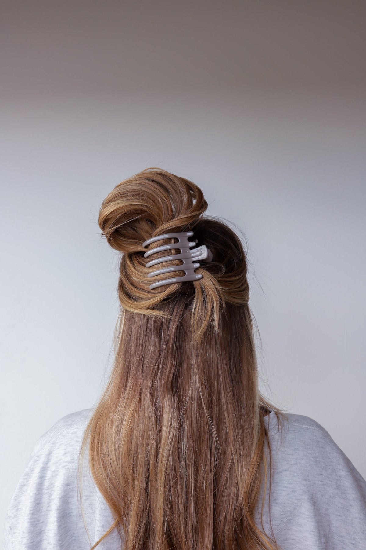 Wide lay down hair claw in shiny light gray, clipped on long hair.