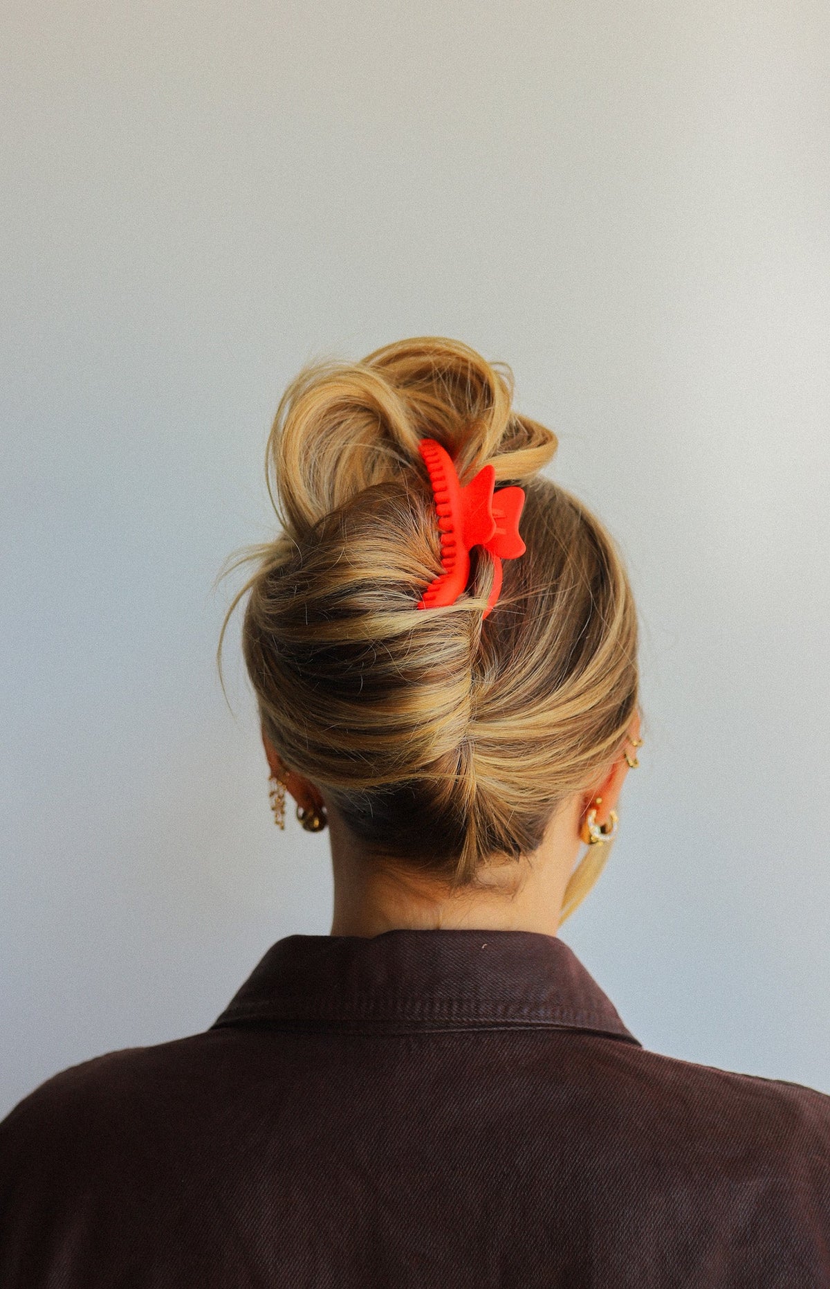 Wavy hair claw clip holding blonde hair bun, red