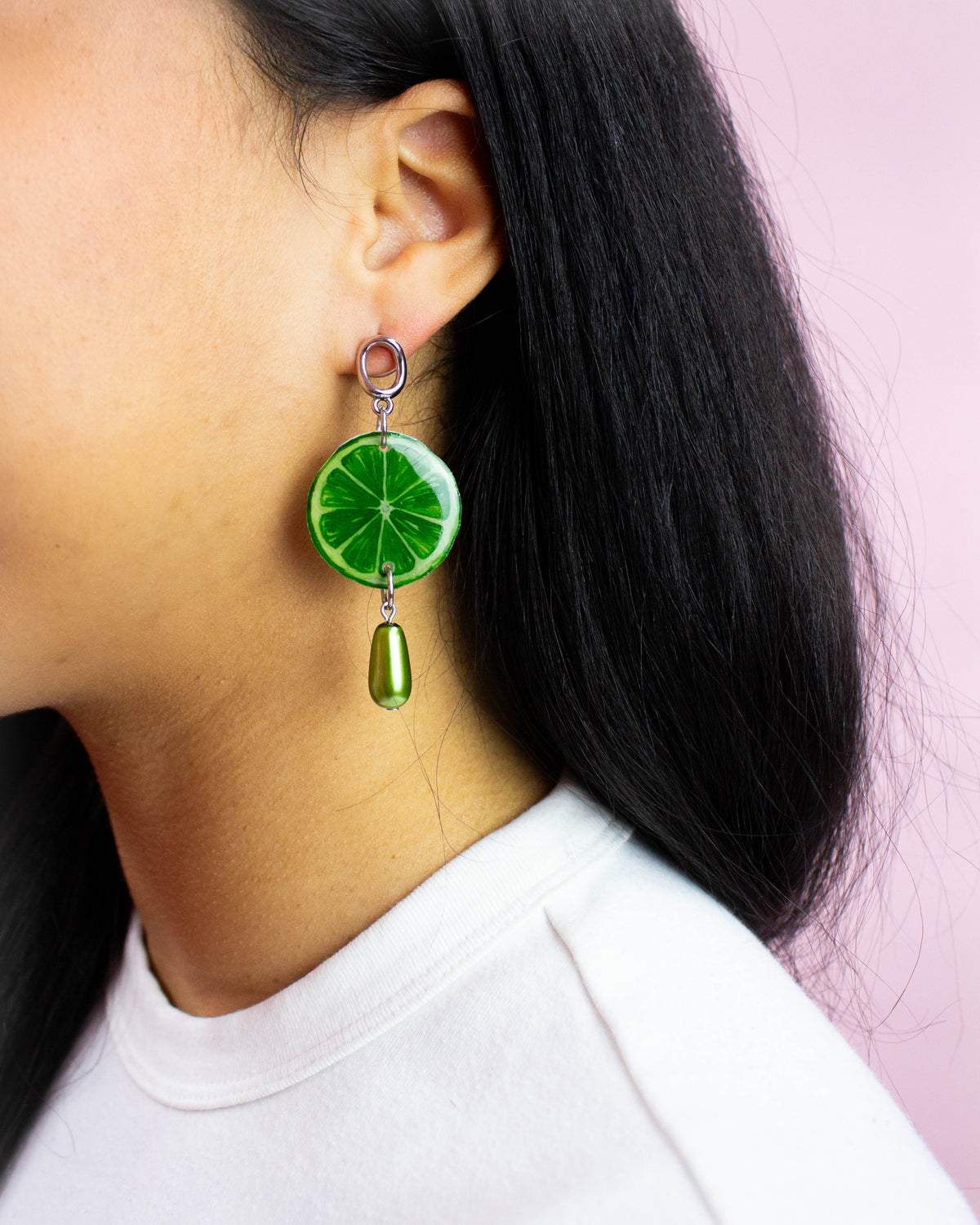 Green lime drop earring with citrus slice charm, worn on the ear