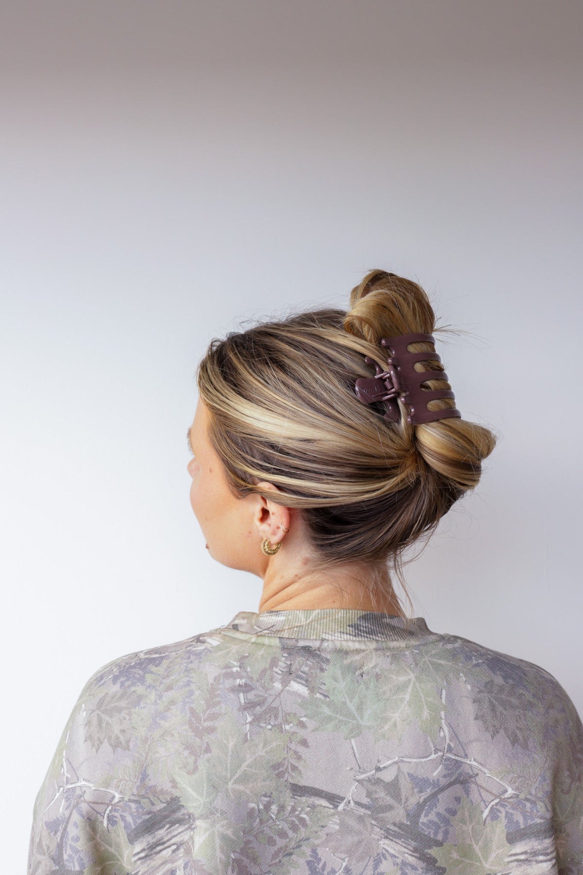 Wide lay down hair claw in shiny burgundy, clipped over hair updo.
