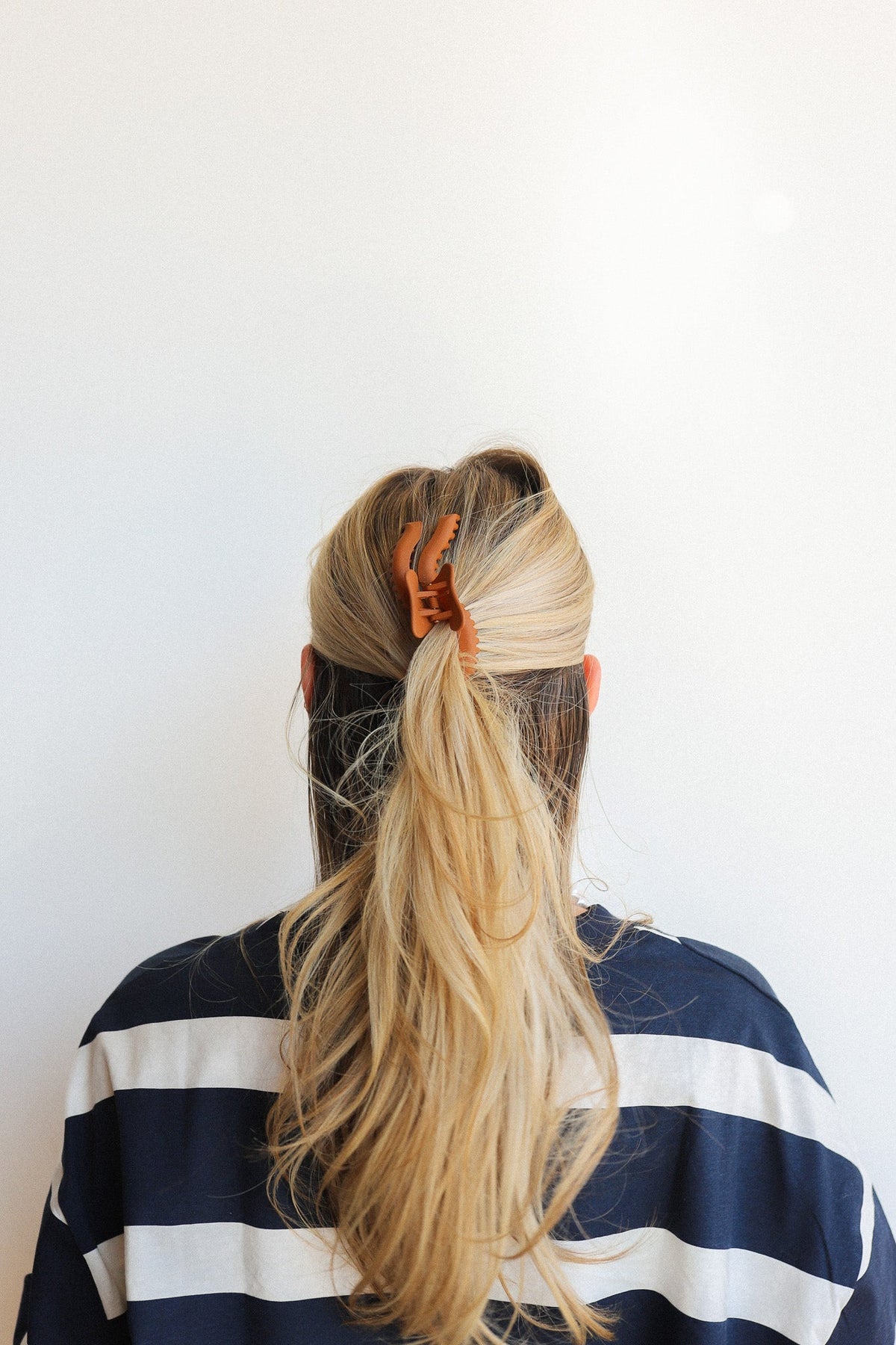 Wavy hair claw clipped in long blonde hair ponytail, back view