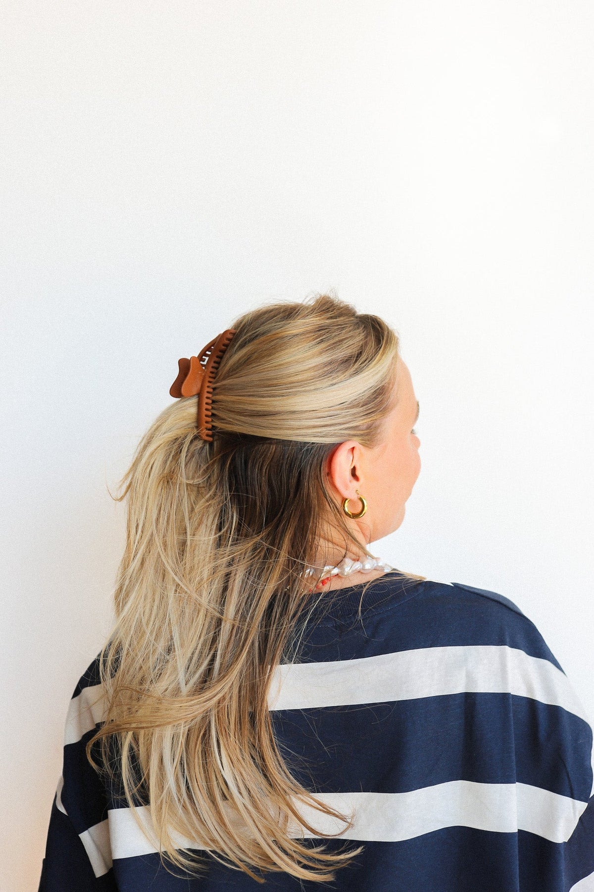 Wavy hair claw clip in warm orange, holding blonde hair in a ponytail