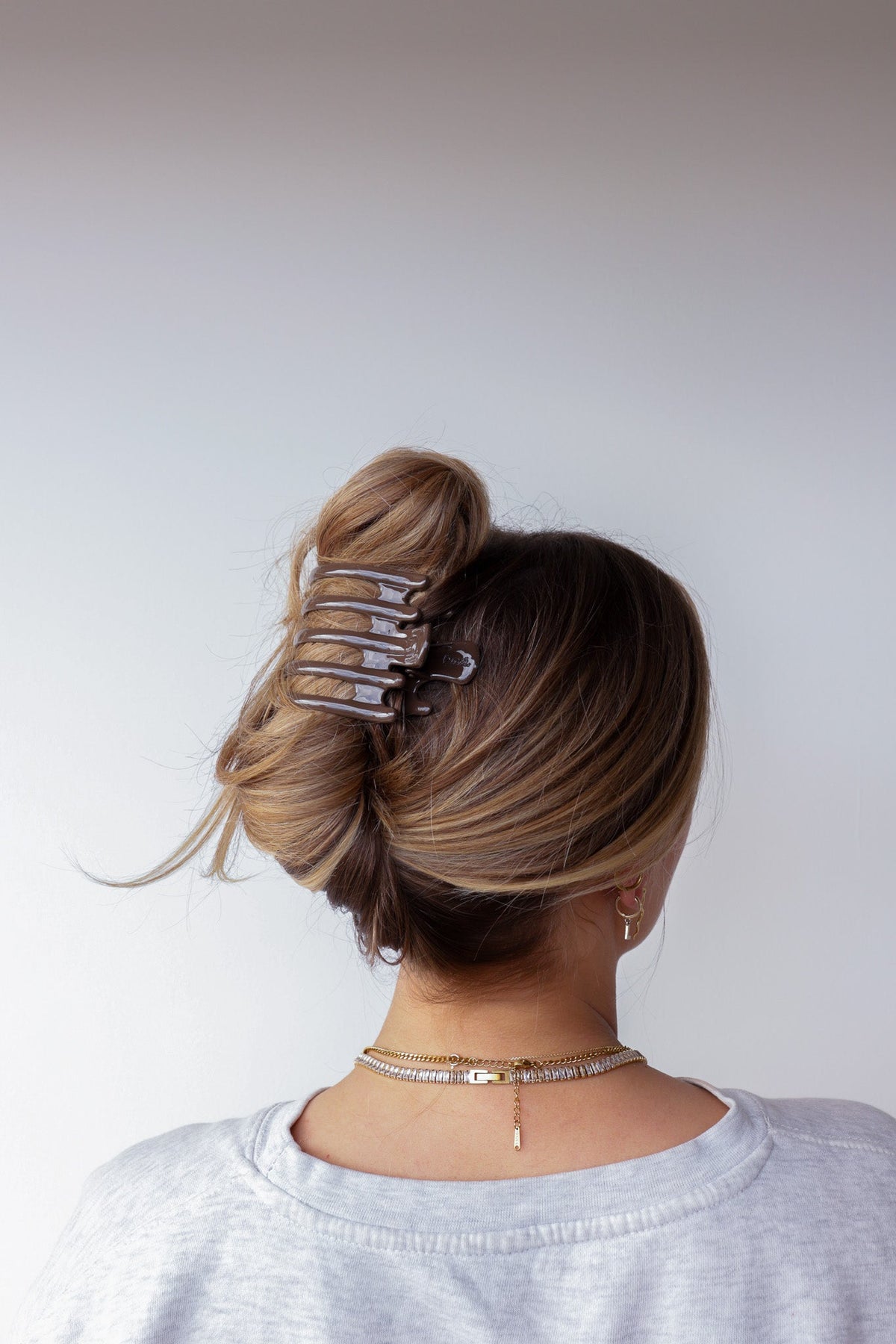 Wide hair claw clip in dark brown glossy tortoise pattern on hair bun