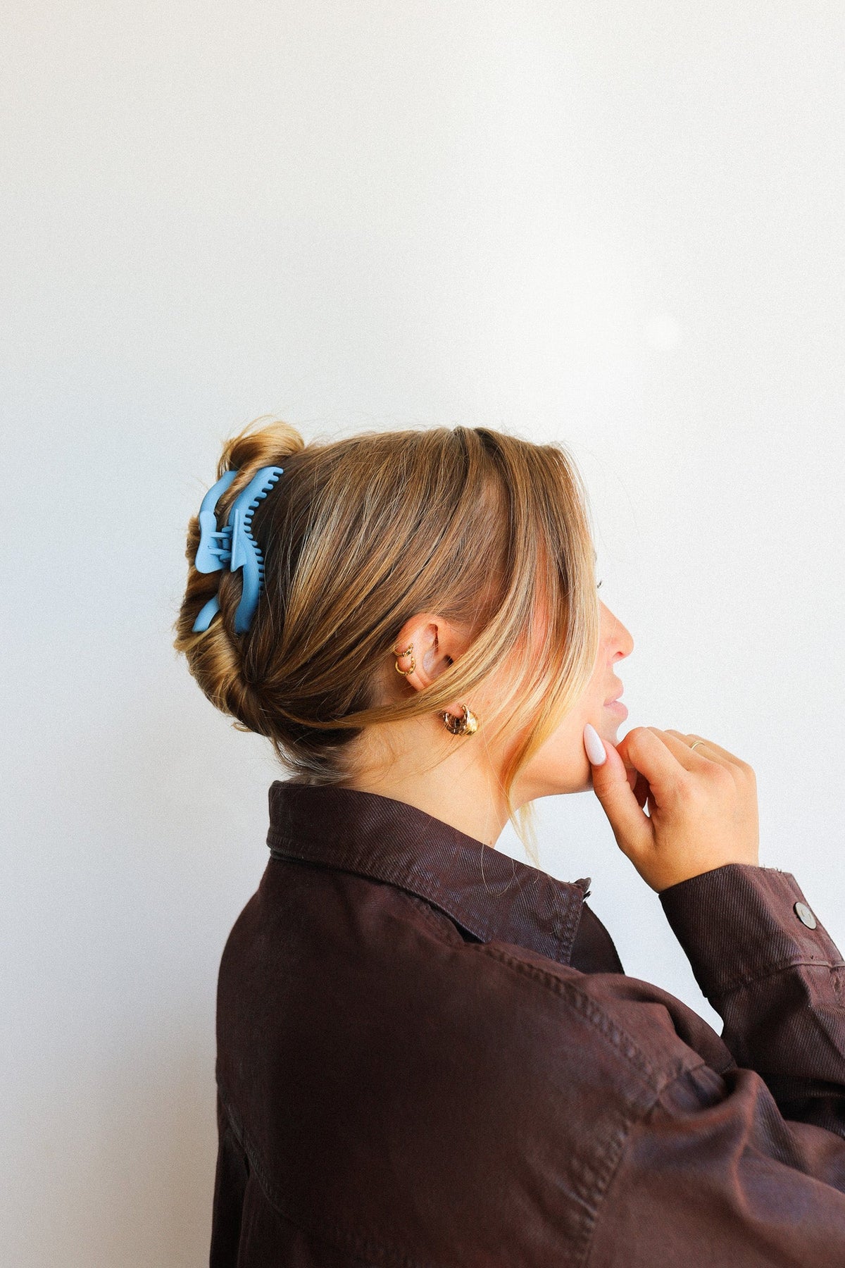 Wavy hair claw clip holding blonde hair in a bun, light blue