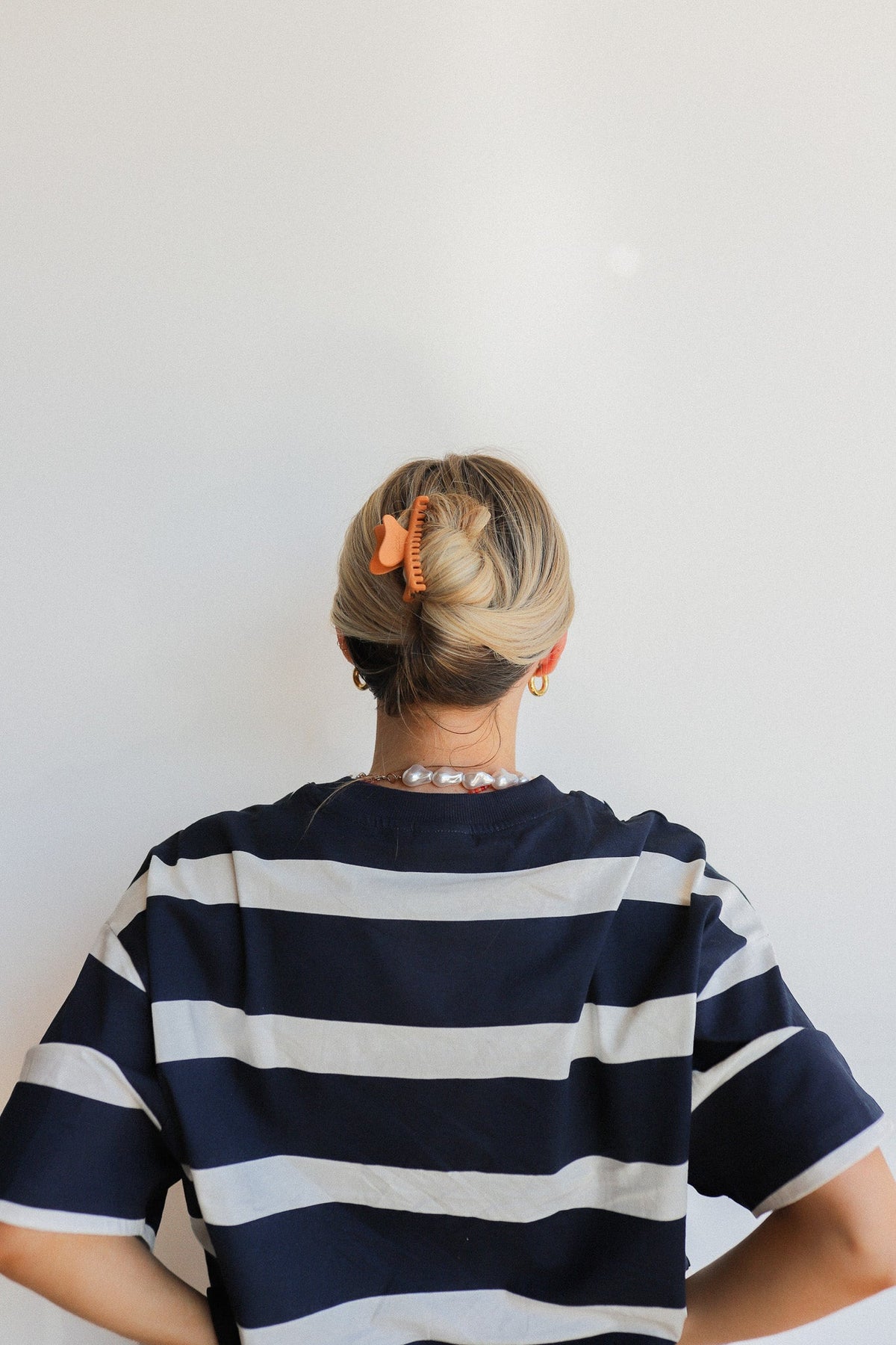 Wavy mini hair claw, orange finish holding a low bun