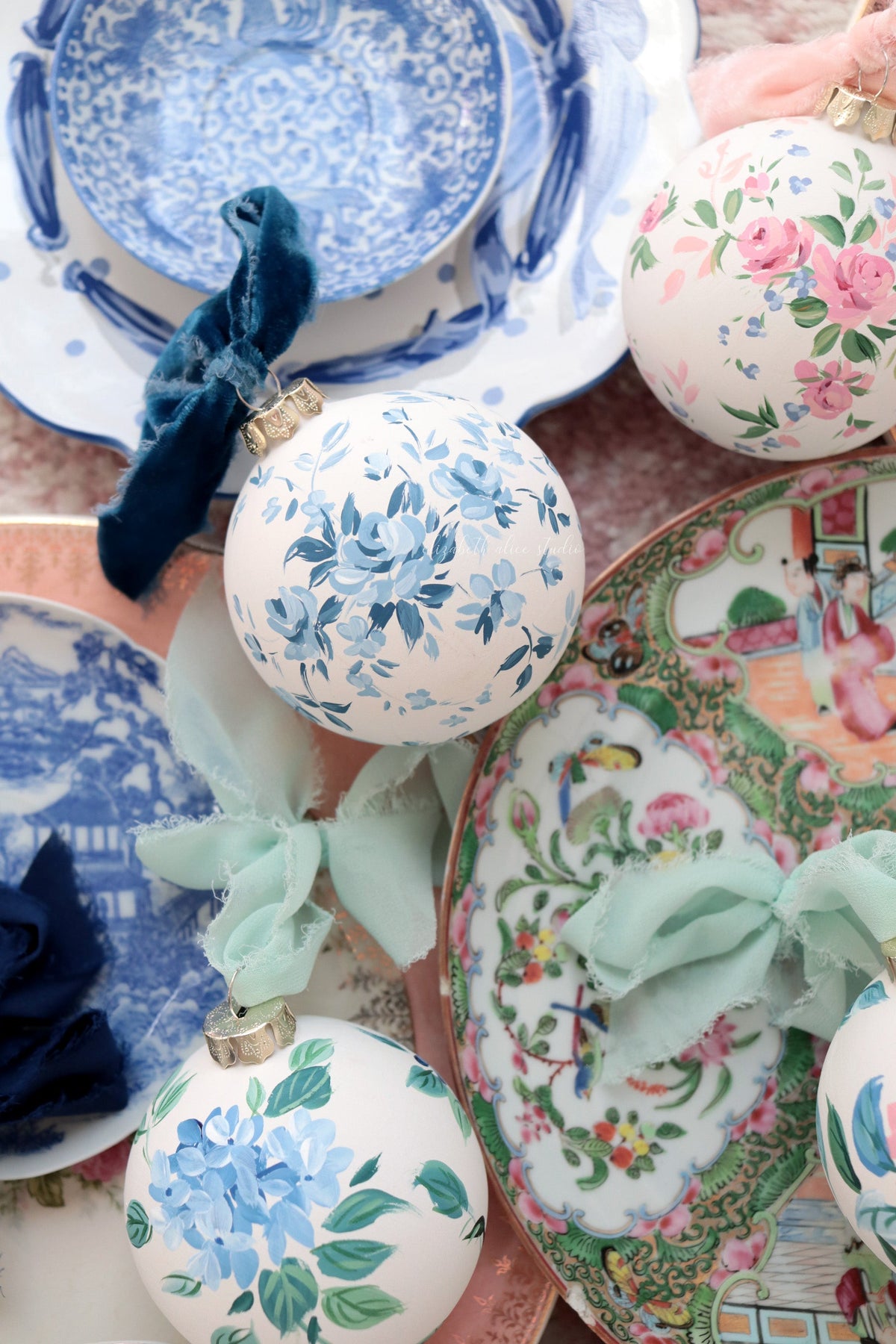 Blue rose ornament with a navy bow among other floral ornaments