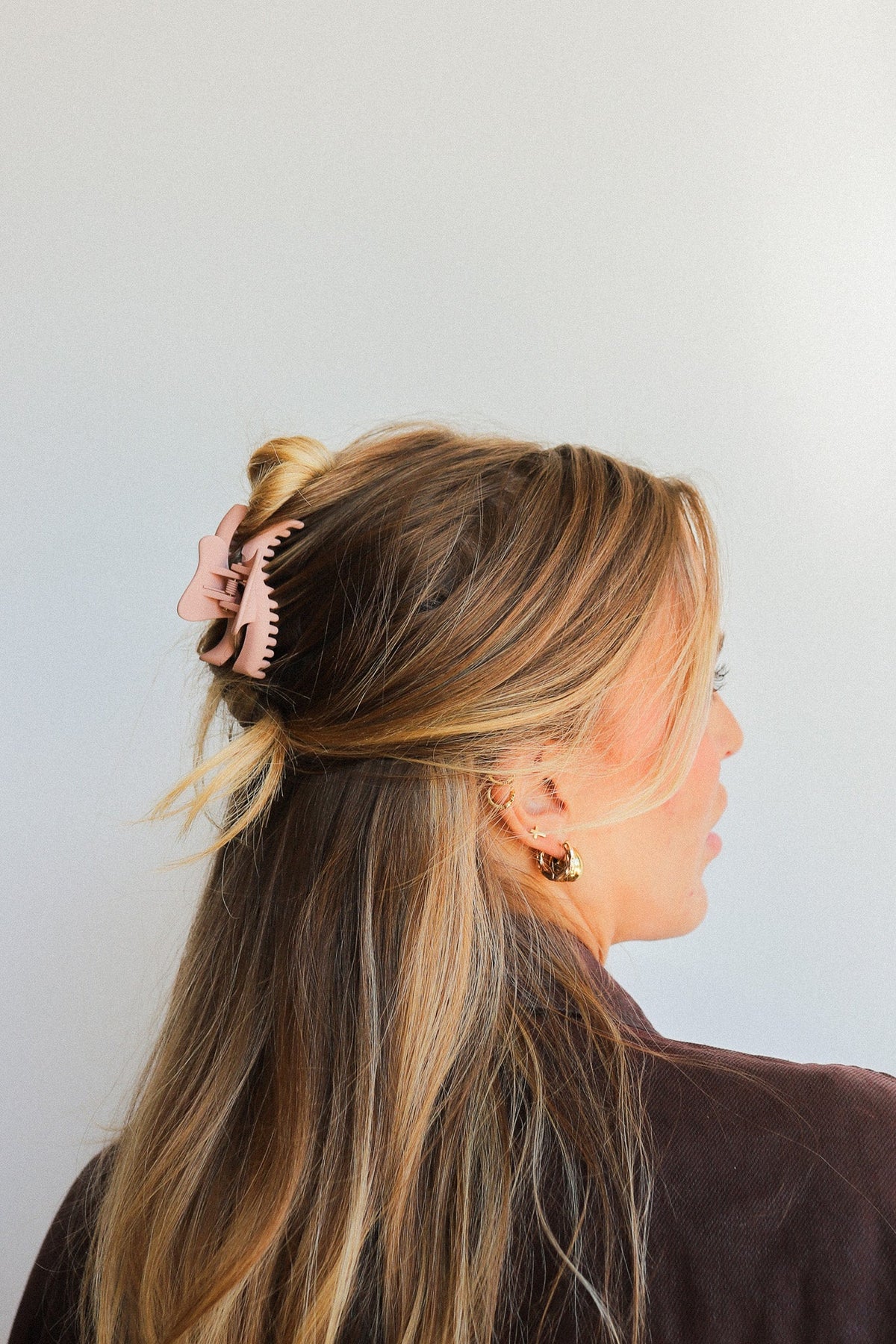 Wavy mini claw hair clip in light pink on long brown hair.