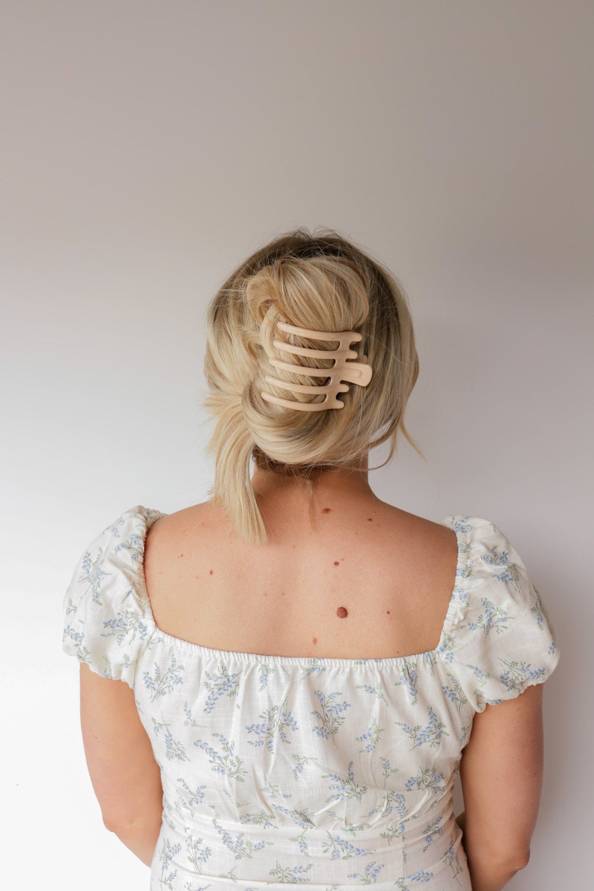 Wide light-tan hair claw with five teeth clipped in blonde hair, back view