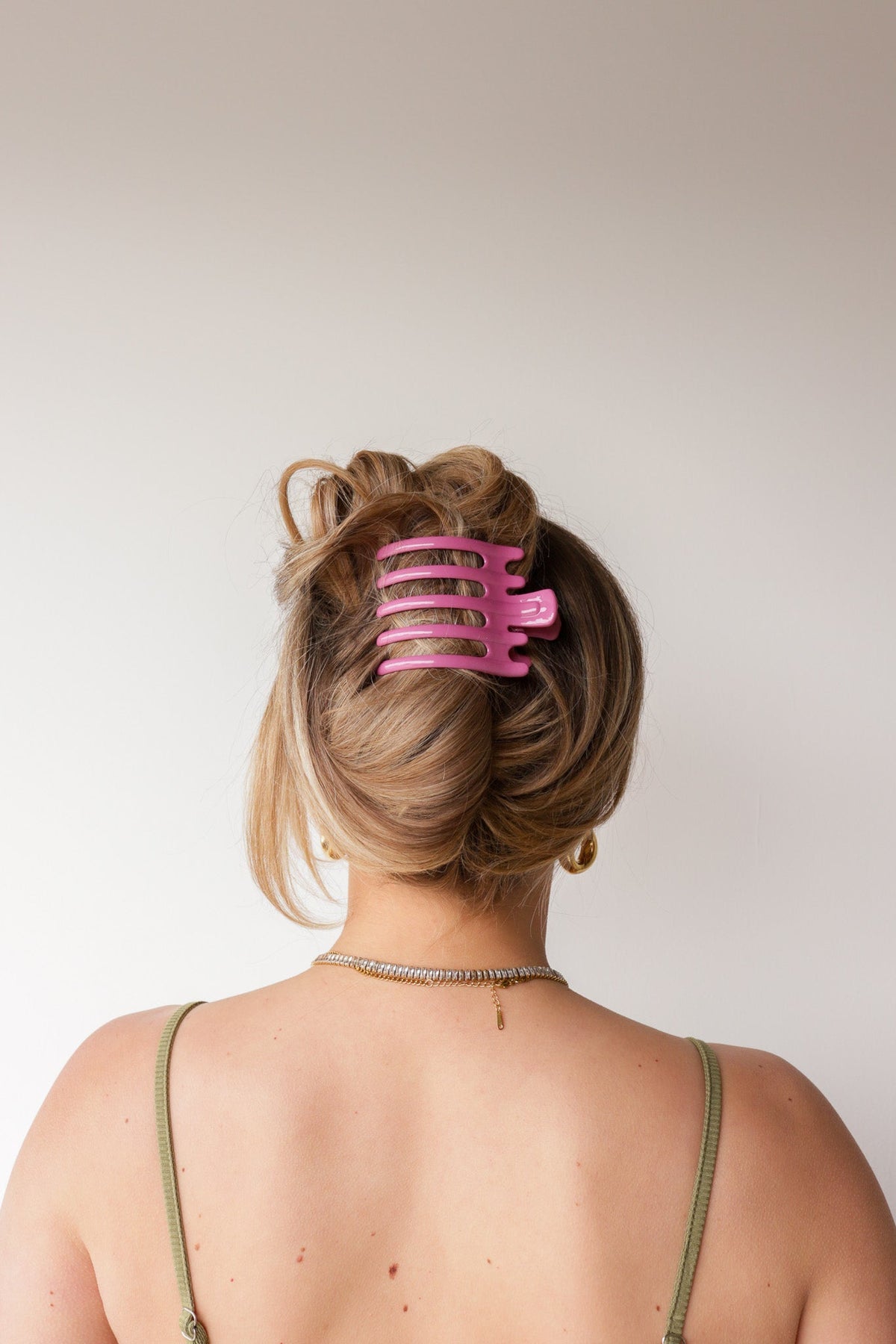Wide pink hair claw with five teeth clipped in blonde updo, back view