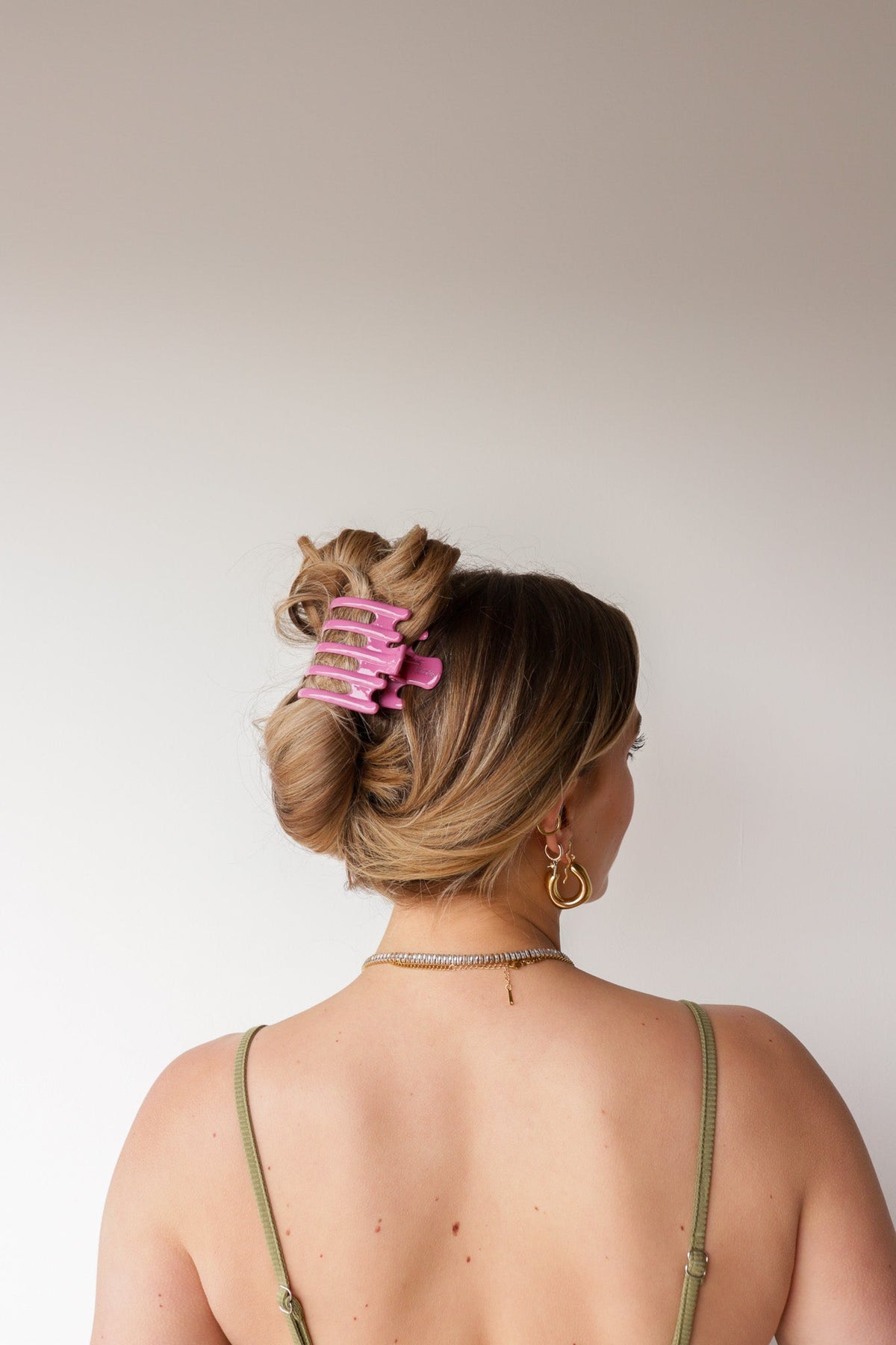 Wide lay-down hair claw, shiny pink; clips up blonde hair at the crown