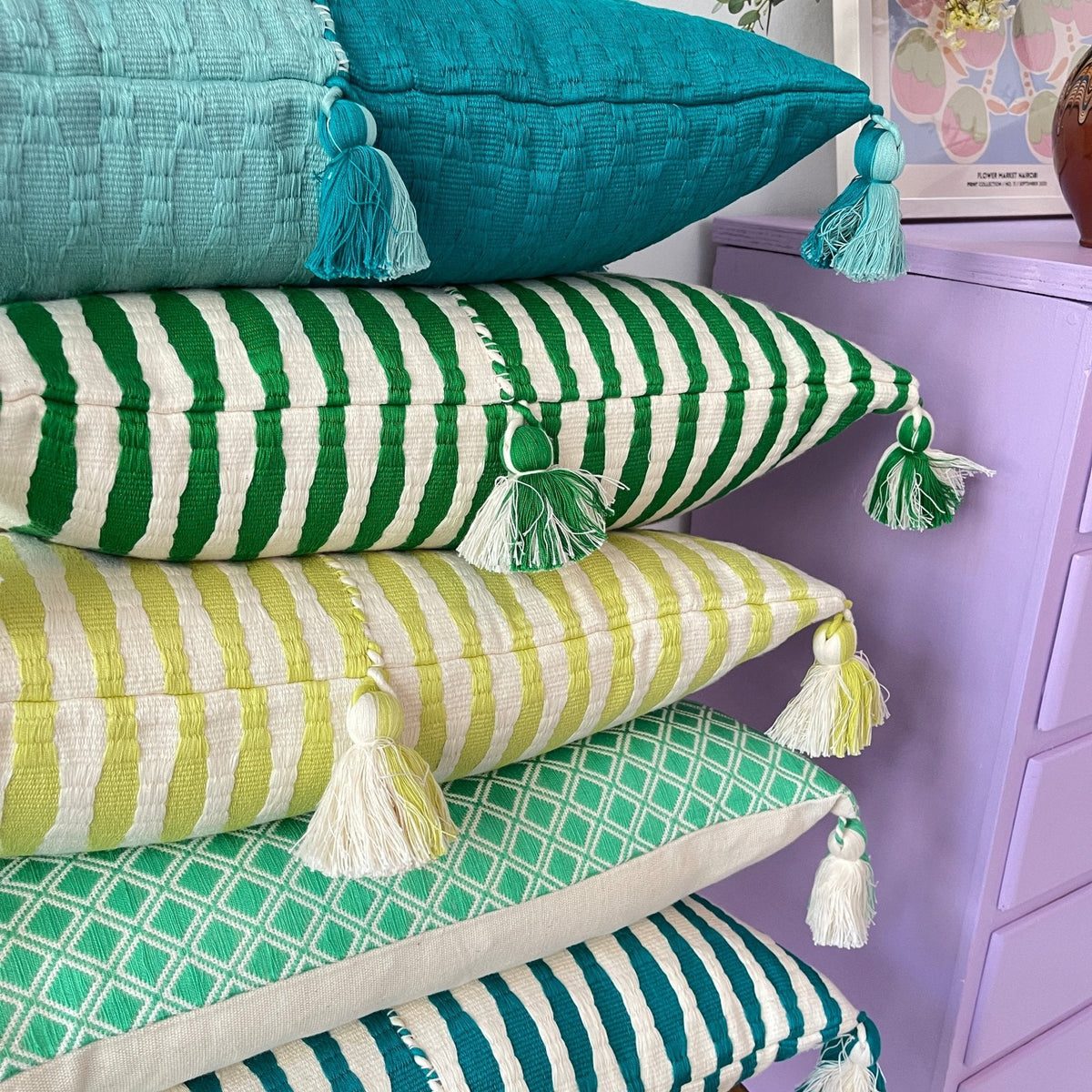 Teal and striped green throw pillows with tassel tassels on corners