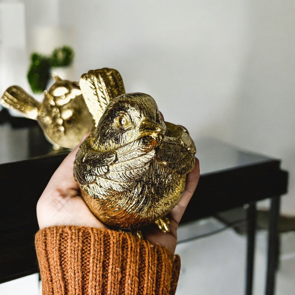 Golden wise bird figurine held in hand, showing detailed feathers.